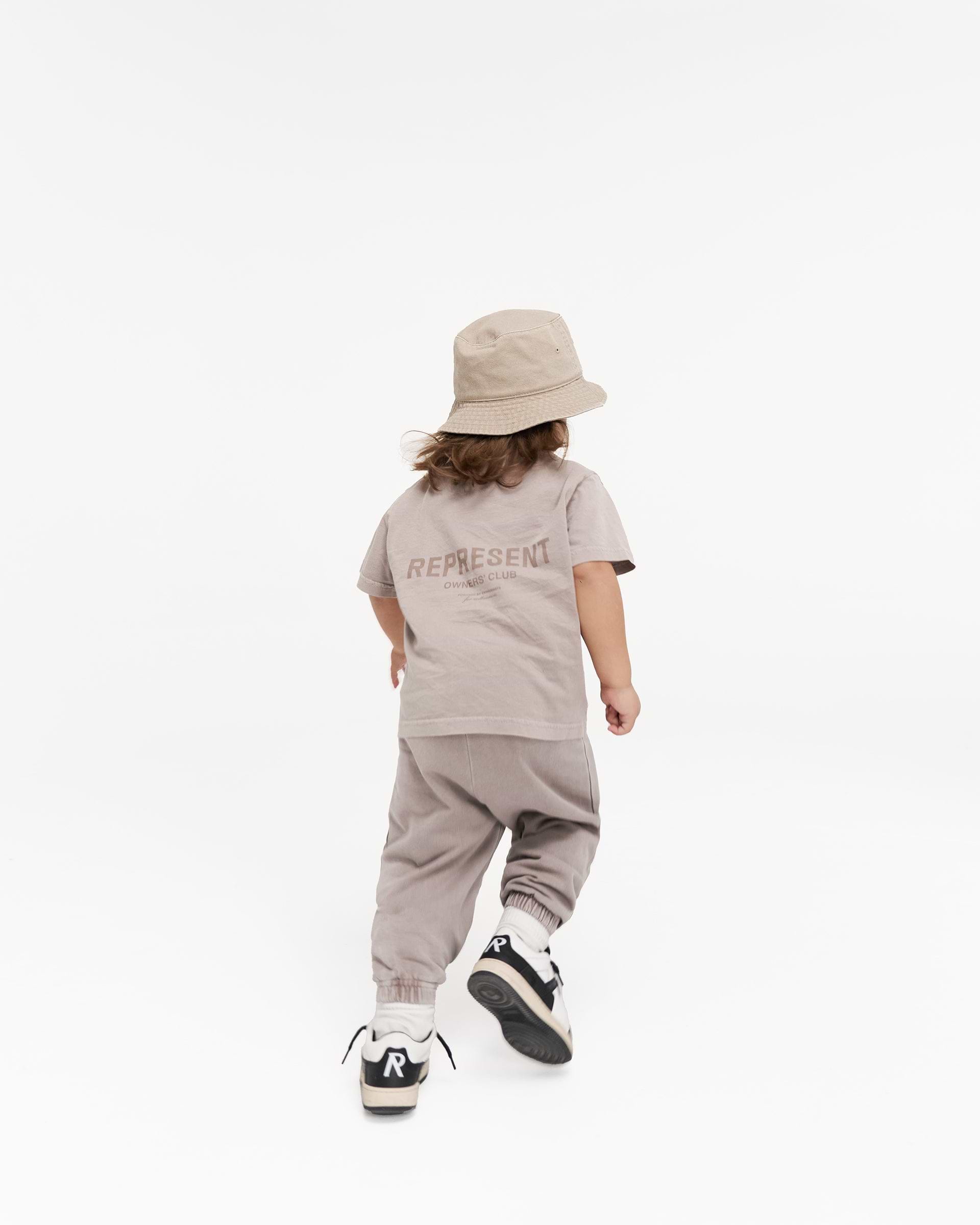 Child wearing mushroom joggers on a plain white background | Represent Mini Owners Club Sweatpants in Mushroom | Children's sweatpants with elasticated waistband | Owners Club Pants | Represent Clo