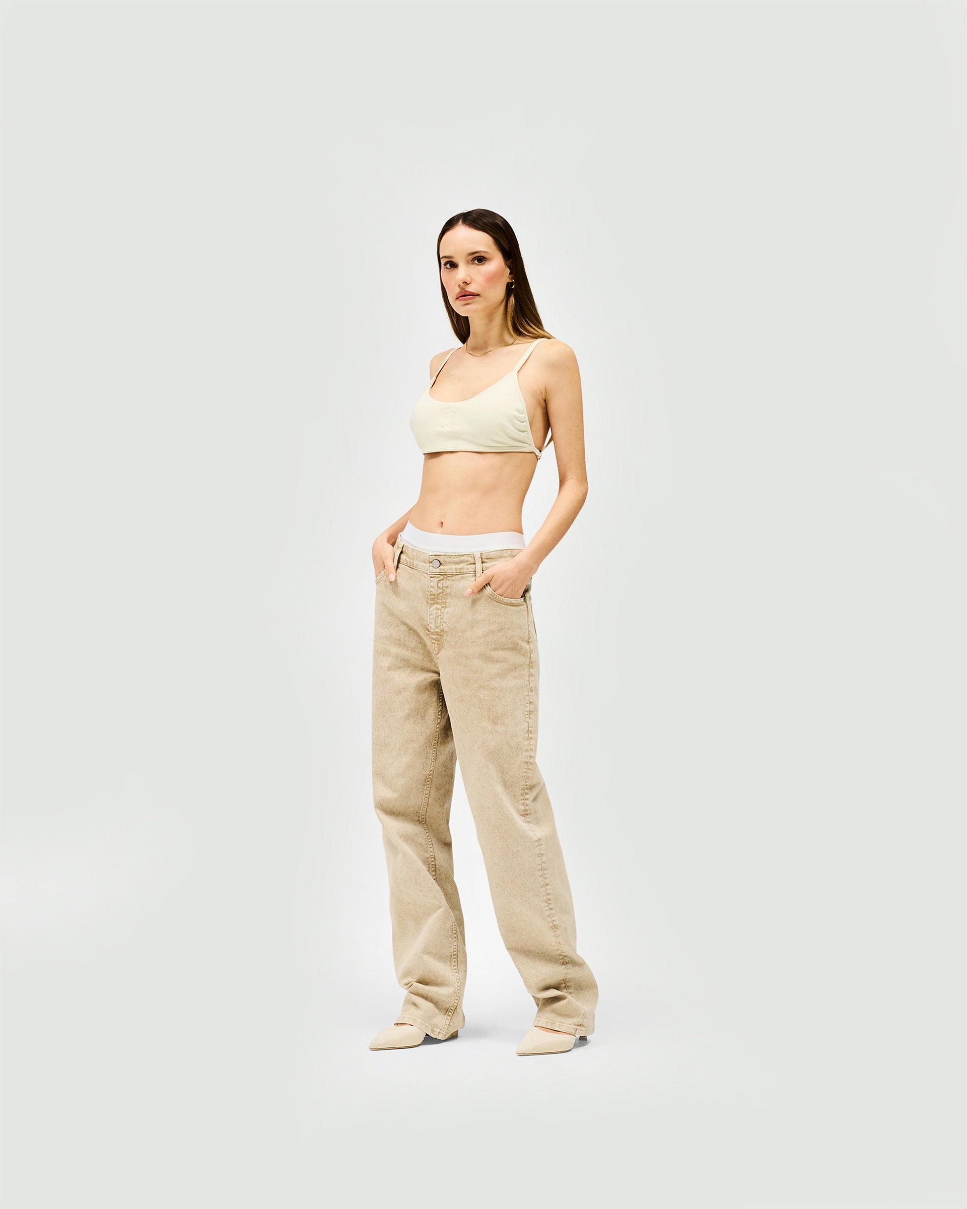 Woman wearing a white bralette on a plain white background | Control Bralette in Warm White | Neoprene bib front bralette with adjustable fit | Womens SS25 Tops | Represent Clo