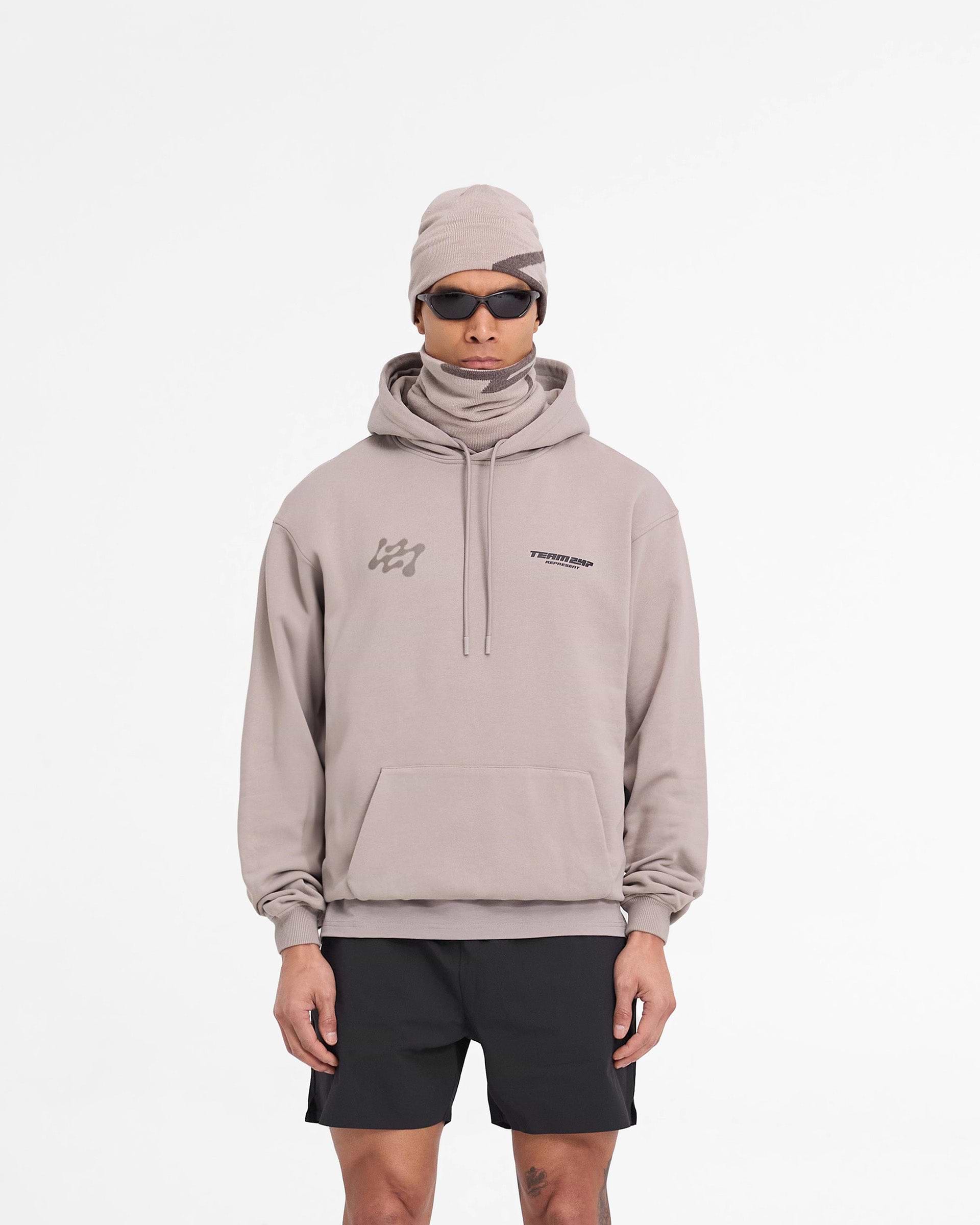 Man wearing an oversized grey hoodie on a plain white background | 247 Future Terrains Oversized Hoodie in Moonrock | Heavyweight jersey cotton hoodie with Team 247 branding | 247 Hoodies | Represent Clo