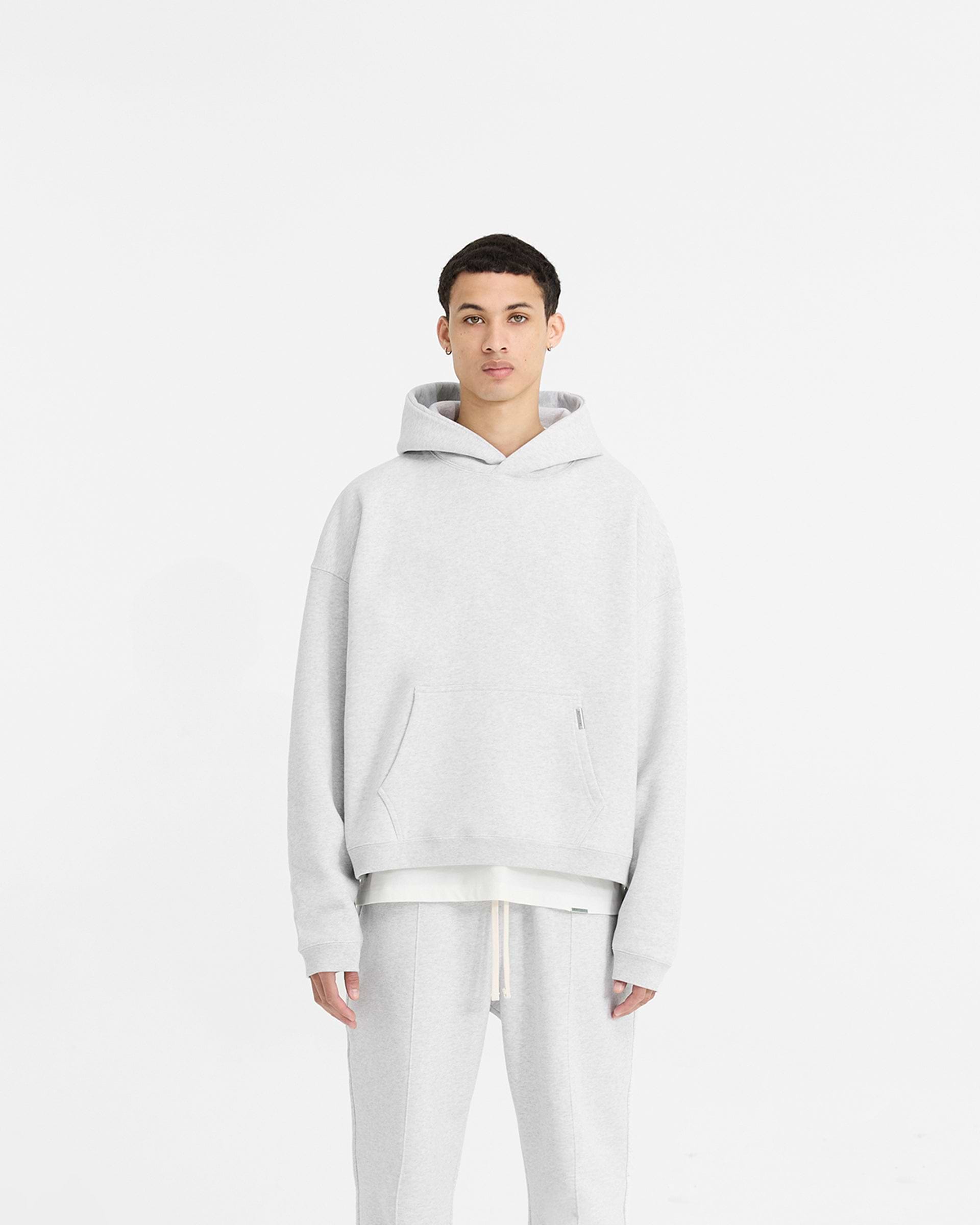 Man wearing an oversized grey hoodie on a plain white background | Initial Boxy Hoodie in Ice Grey Marl | Boxy fit with cropped body and wide sleeves | Initial Hoodies | Represent Clo