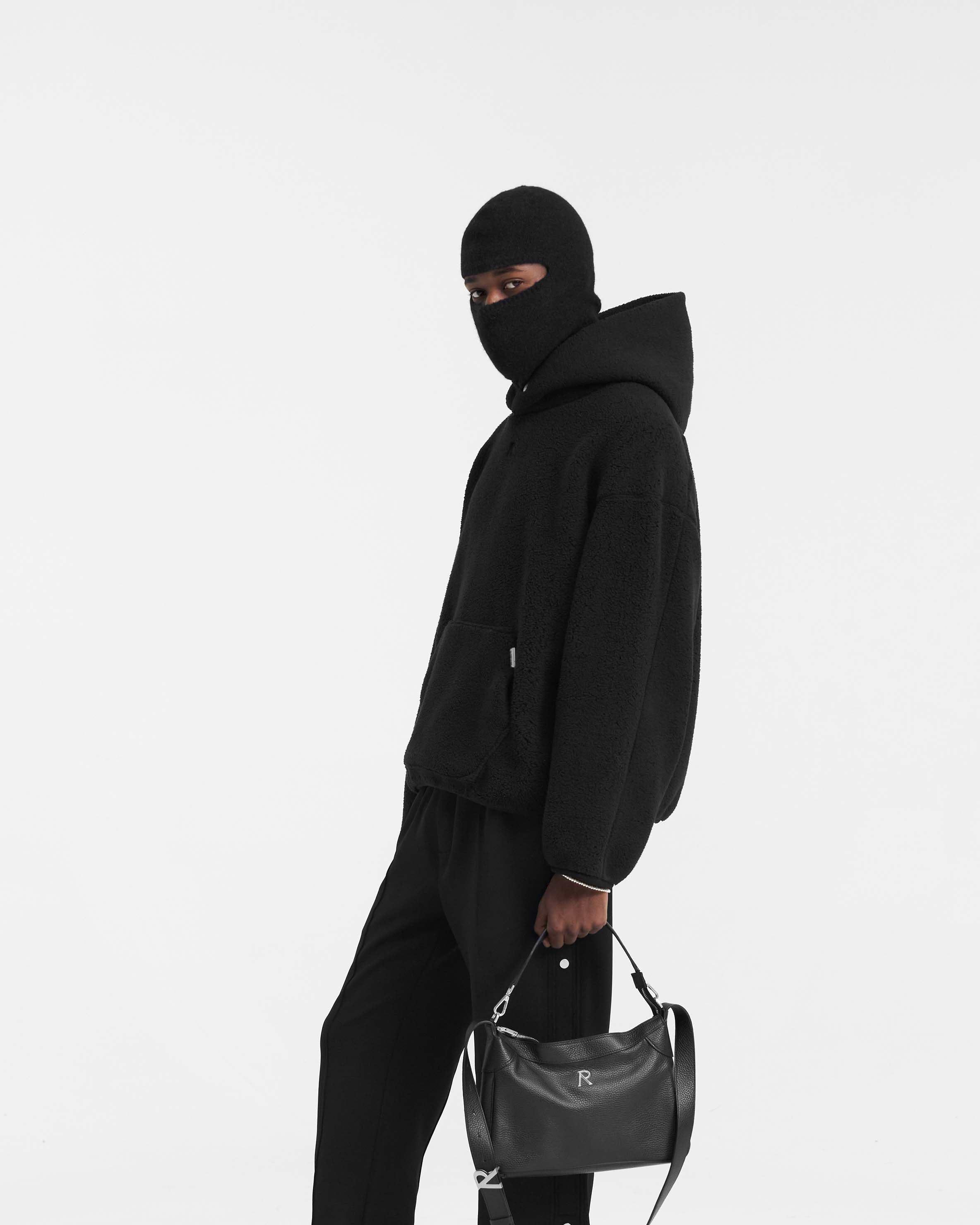 Person wearing an oversized black fleece hoodie on a plain white background | Fleece Oversized Hoodie in Black | Oversized hoodie with embroidered logo and kangaroo pocket | PRE SS24 Hoodies | Represent Clo
