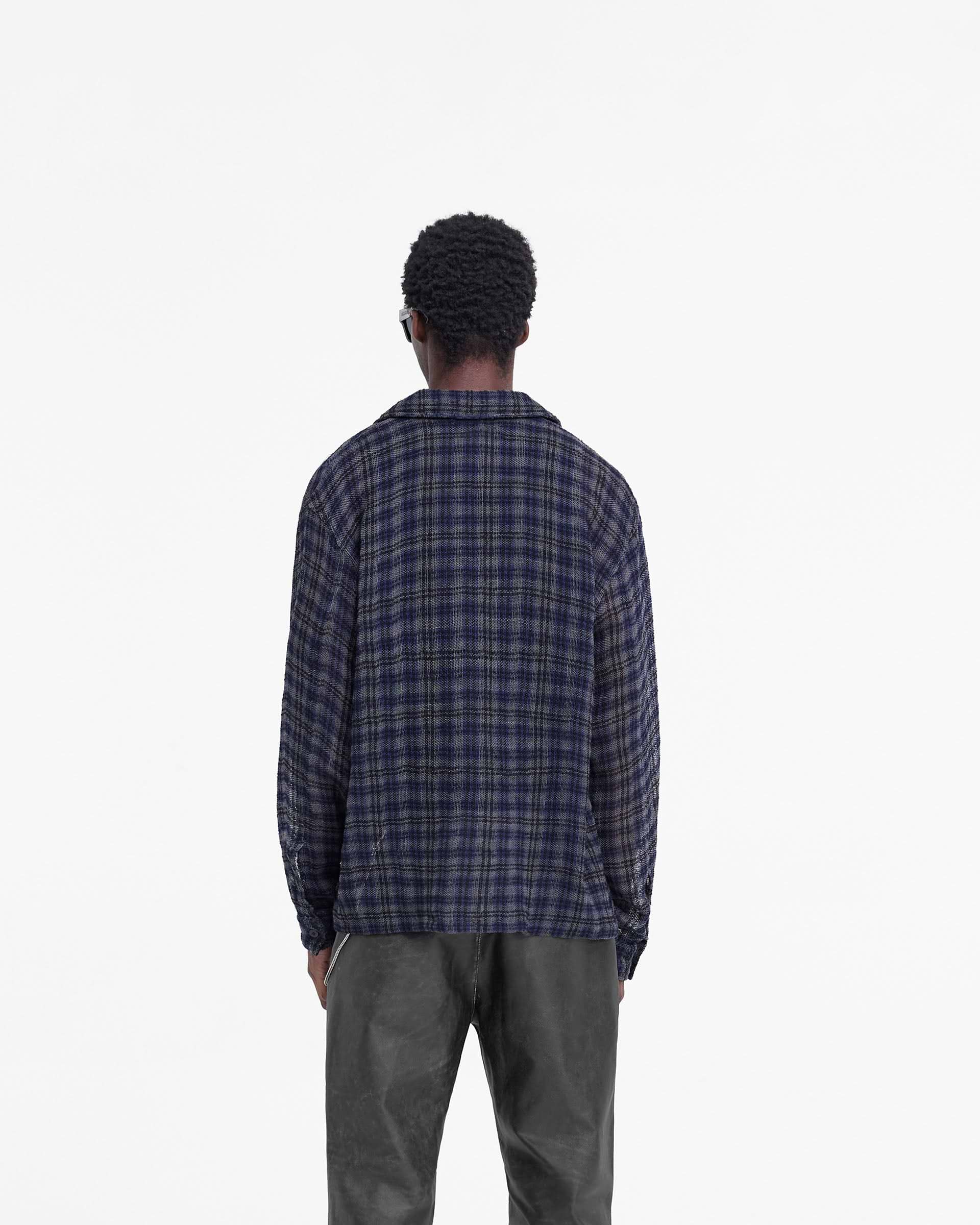 Man wearing a blue check flannel shirt on a plain white background | Check Flannel Shirt in Blue Check | Oversized flannel shirt with flap pockets and button-up front | FW24 Shirts | Represent Clo