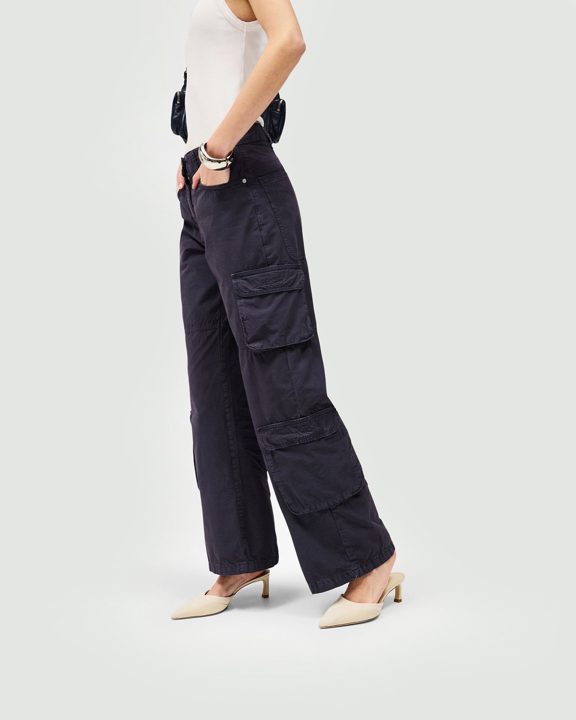 Woman wearing blue cargo trousers on a plain white background | Fender Cargo in Steel Blue | Wide leg cargo trousers with ripstop fabric | Womens SS25 Bottoms | Represent Clo