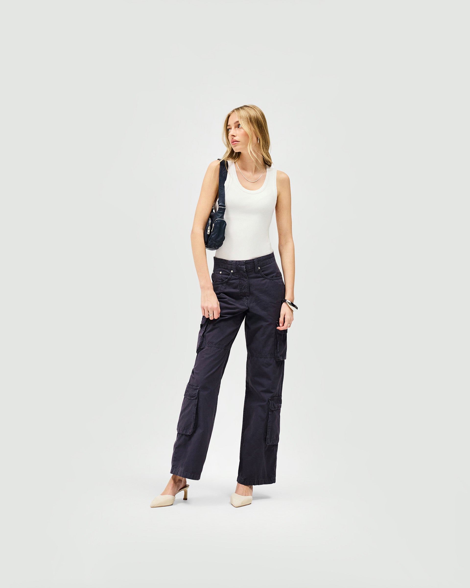 Woman wearing steel blue cargo trousers on a plain white background | Fender Cargo in Steel Blue | Wide-leg cargo trousers with cargo pockets | Womens SS25 Bottoms | Represent Clo