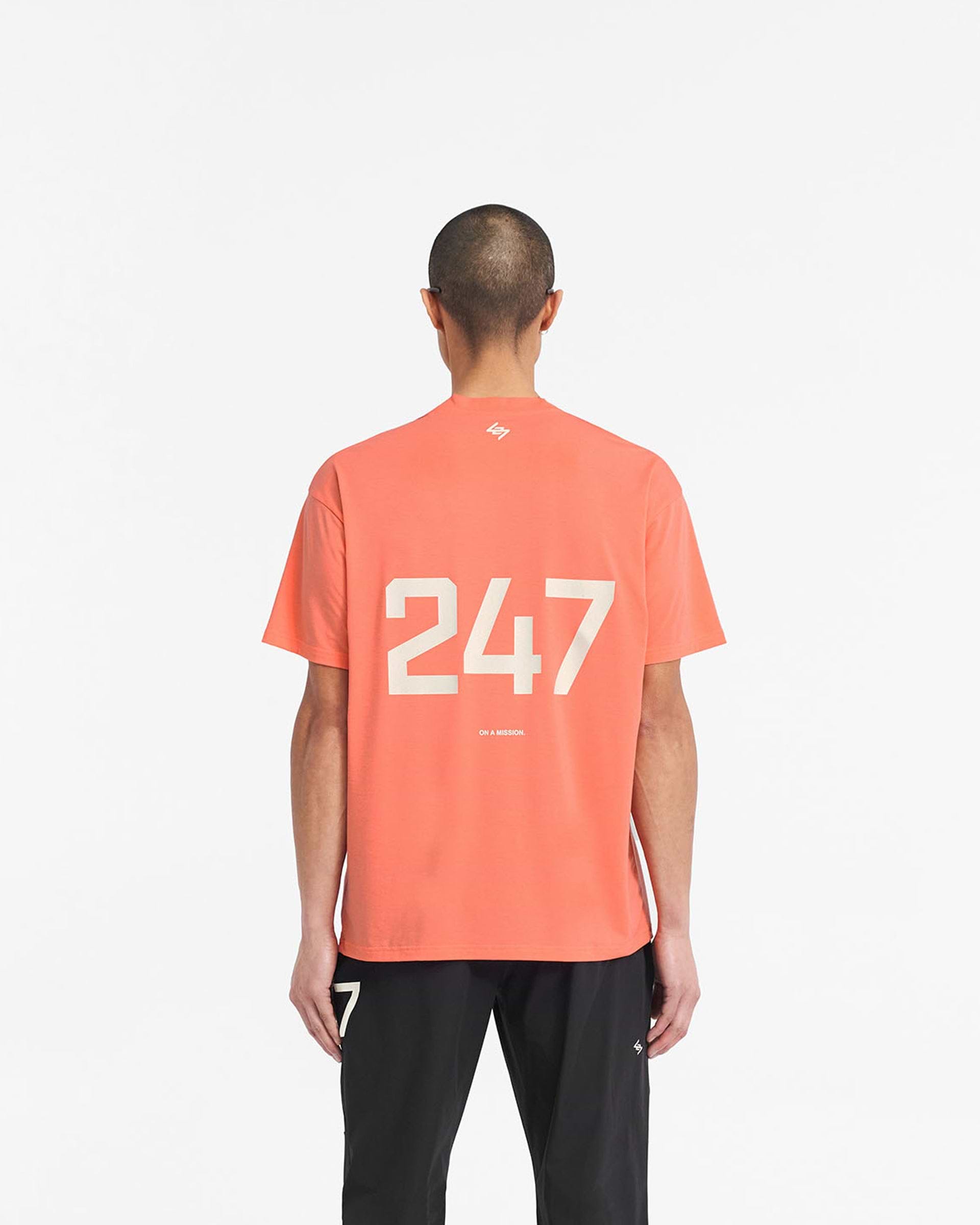 Man wearing an oversized coral t-shirt on a plain white background | 247 Oversized T-Shirt in Coral | Lightweight gym t-shirt with quick dry fabric | 247 T-Shirts | Represent Clo