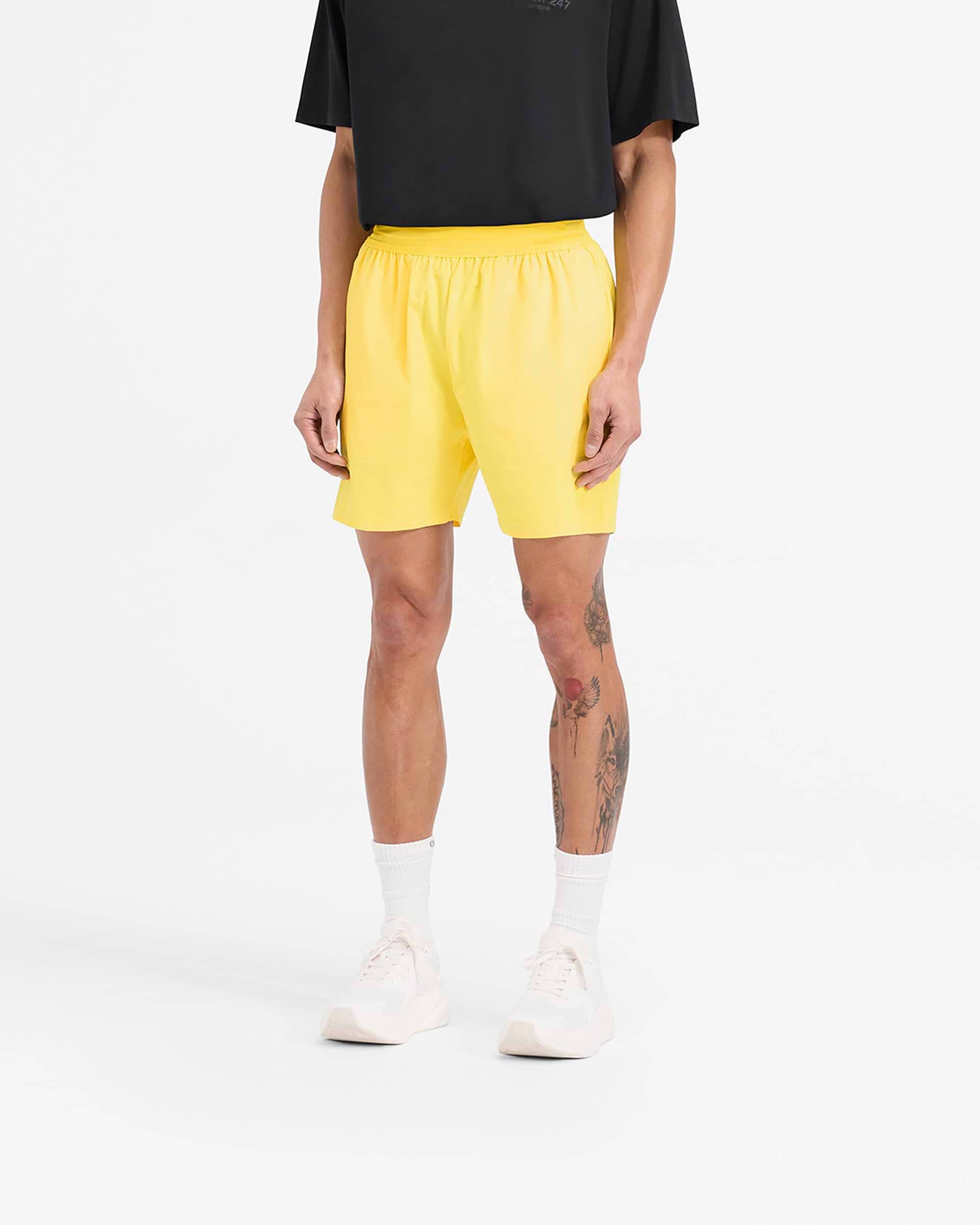 Man wearing yellow gym shorts on a plain white background | Team 247 Fused Shorts in Lemon | Quick drying shorts with reverse coil zippers | 247 Shorts | Represent Clo