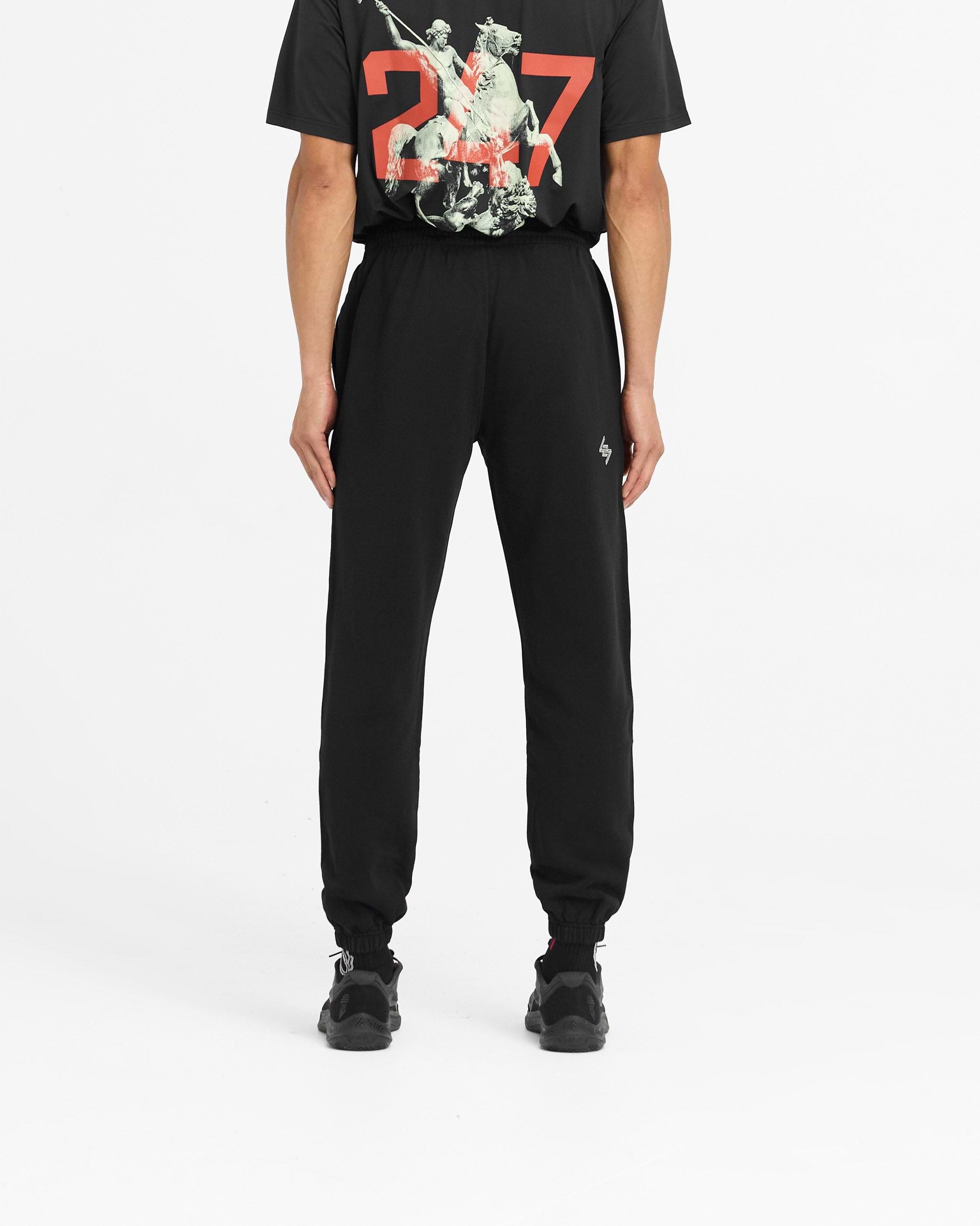 Man wearing black sweatpants on a plain white background | 247 Berlin Sweatpant in Black | Sweatpants with elasticated cuffs and zip pocket | 247 Pants | Represent Clo