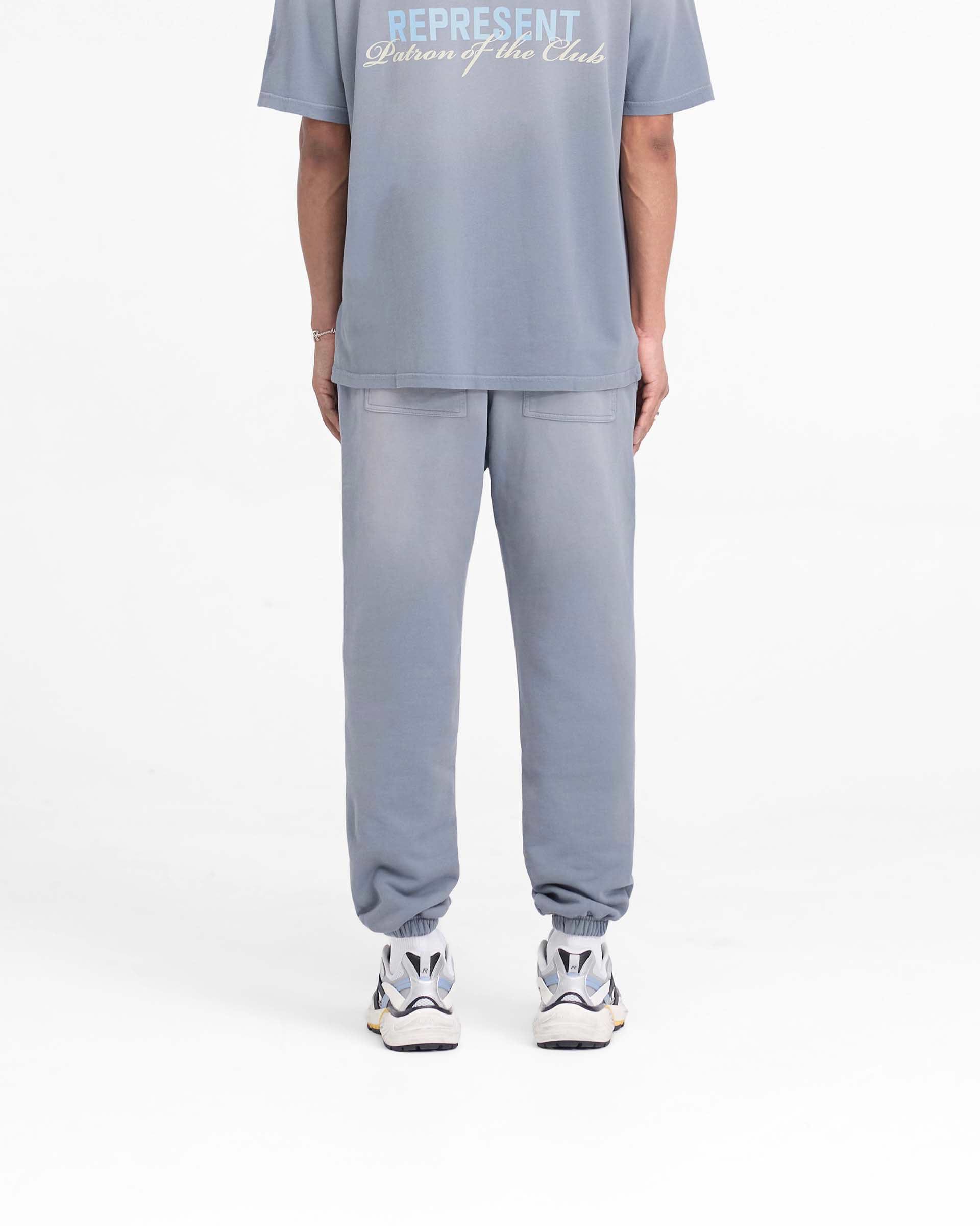 Man wearing grey sweatpants on a plain white background | Patron Of The Club Sweatpant in Washed Grey | Sweatpants with elasticated waistband and cuffs | Patrons Pants | Represent Clo