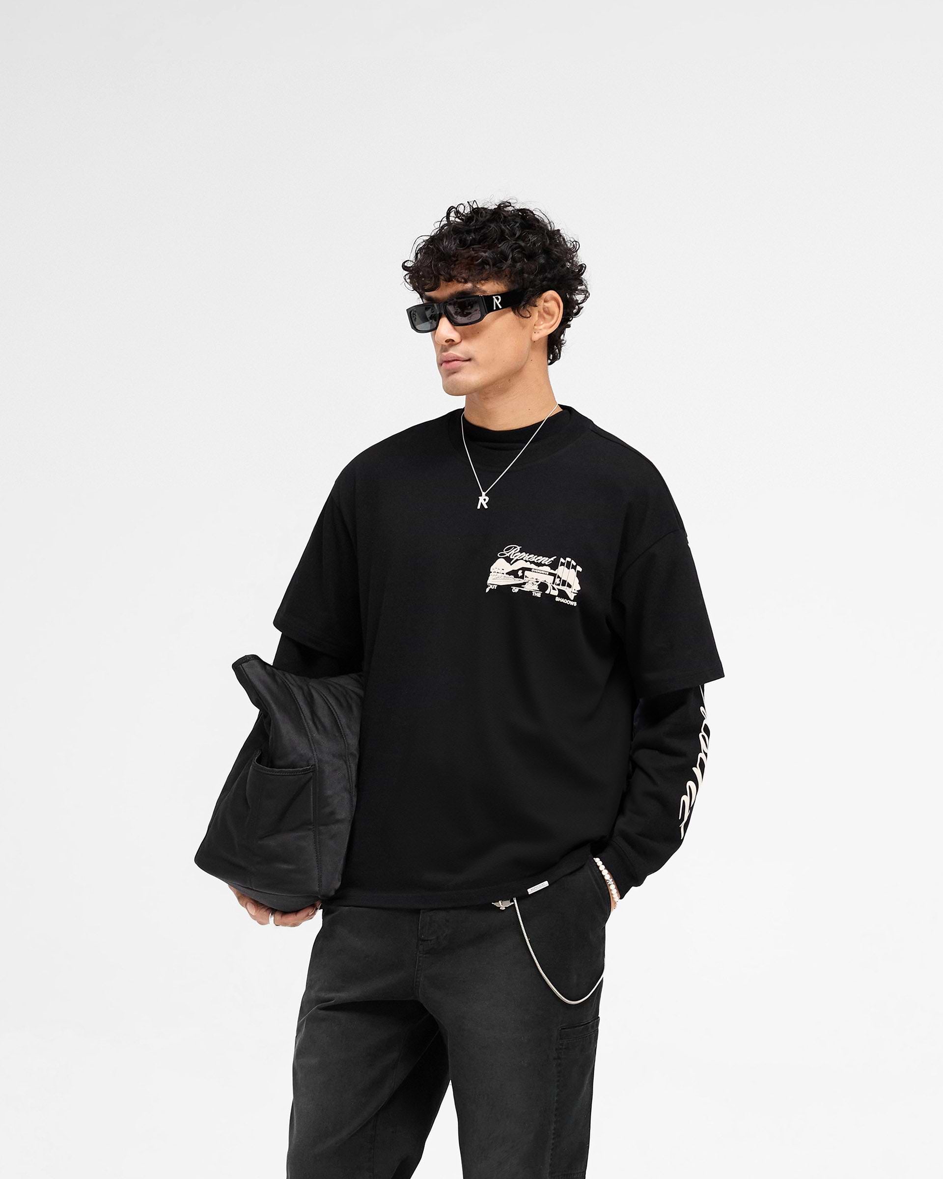 Man wearing a black t-shirt on a plain white background | Raceway T-Shirt in Jet Black | Slightly oversized t-shirt with puff print graphic | SS25 T-Shirts | Represent Clo