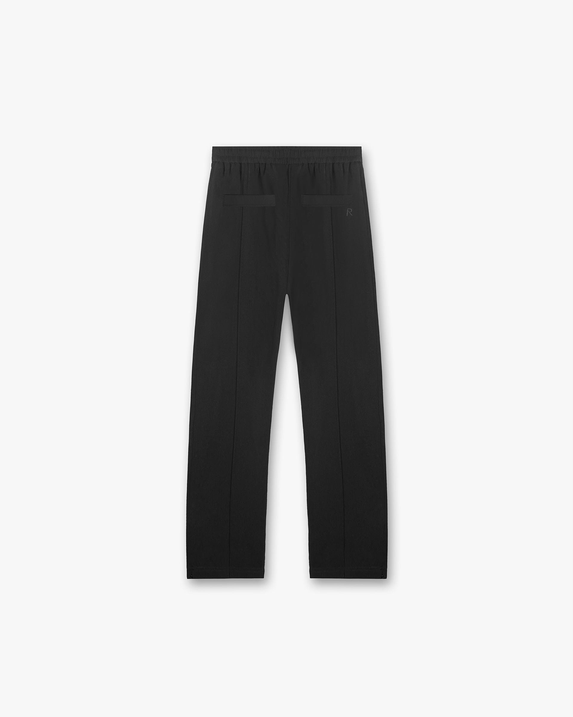 Back product image of mens black track pants on a plain white background | Initial Track Pant in Black | Pants with elasticated waistband and zipped split hems | Initial Pants | Represent Clo