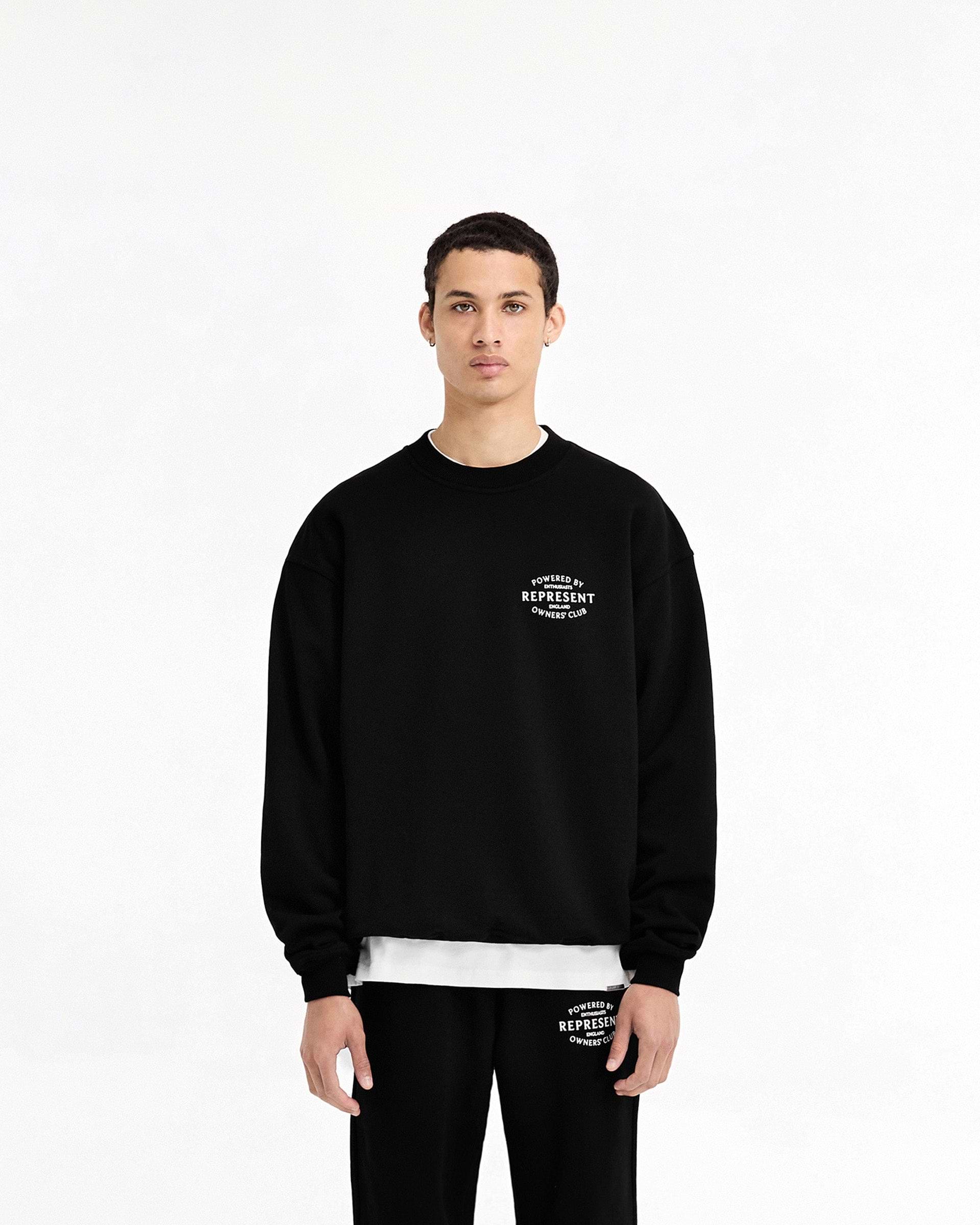 Man wearing a black sweater on a plain white background | Represent Owners Club Stamp Sweater in Jet Black | Oversized fit sweater with ribbed trims | Owners Club Sweaters | Represent Clo