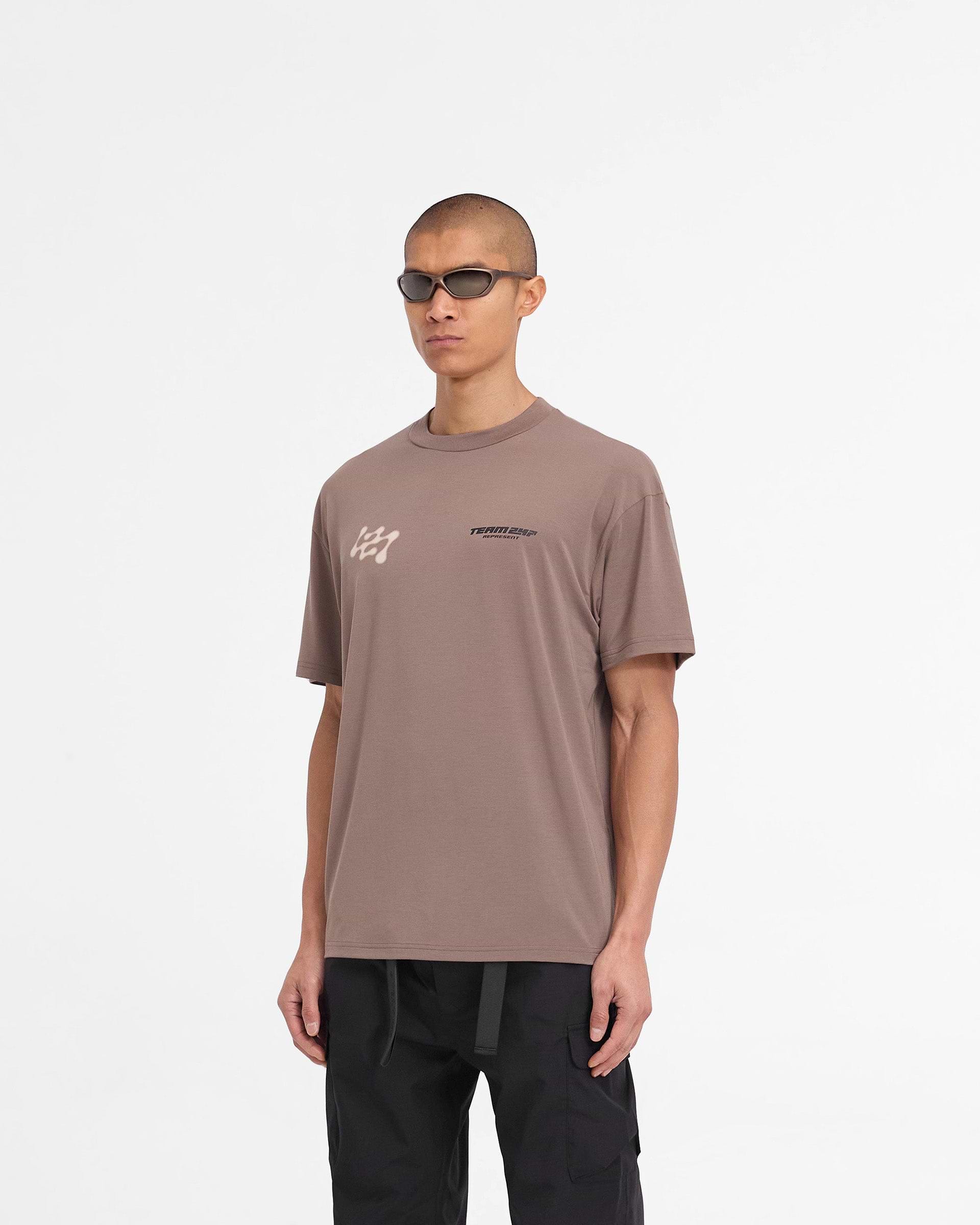 Man wearing an oversized brown t-shirt on a plain white background | 247 Future Terrains Oversized T-Shirt in Umber | Quick drying oversized t-shirt | 247 T-Shirts | Represent Clo