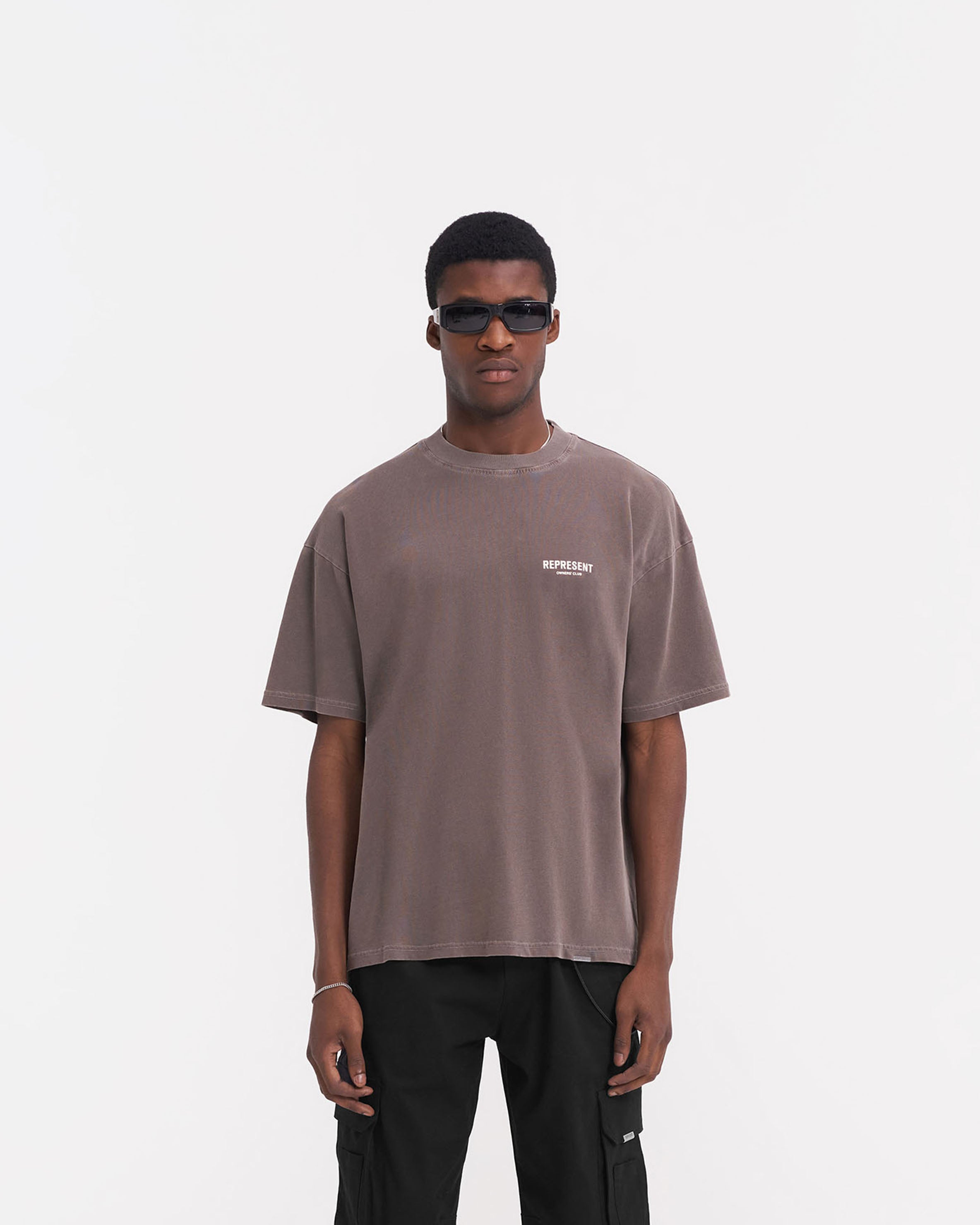 Man wearing an oversized grey t-shirt on a plain white background | Represent Owners Club T-Shirt in Fog | Oversized t-shirt with ribbed crewneck and branding | Owners Club T-Shirts | Represent Clo