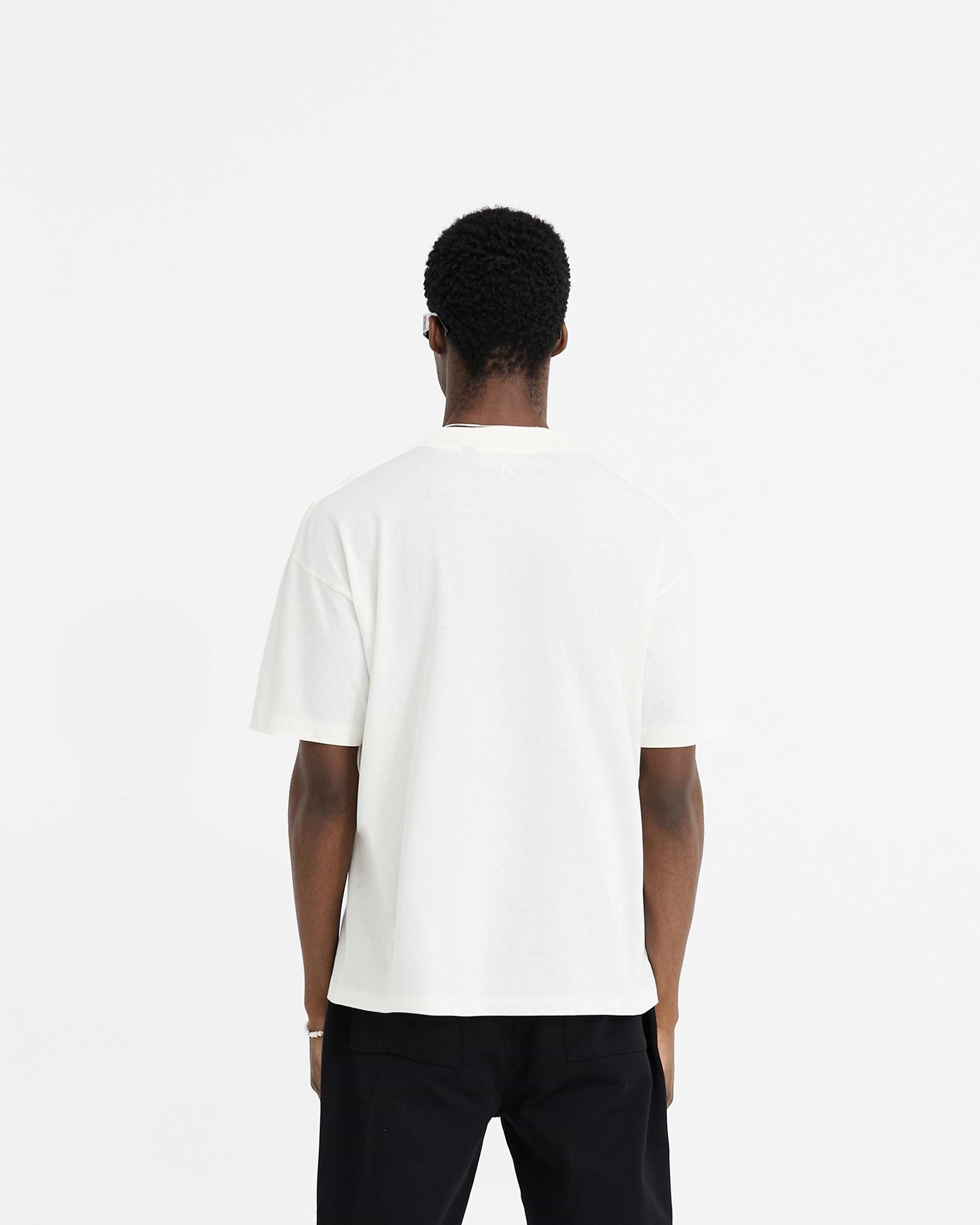 Man wearing a white oversized t-shirt on a plain white background | Initial Oversized T-Shirt in Flat White | Oversized t-shirt with Owners Club fit | Initial T-Shirts | Represent Clo