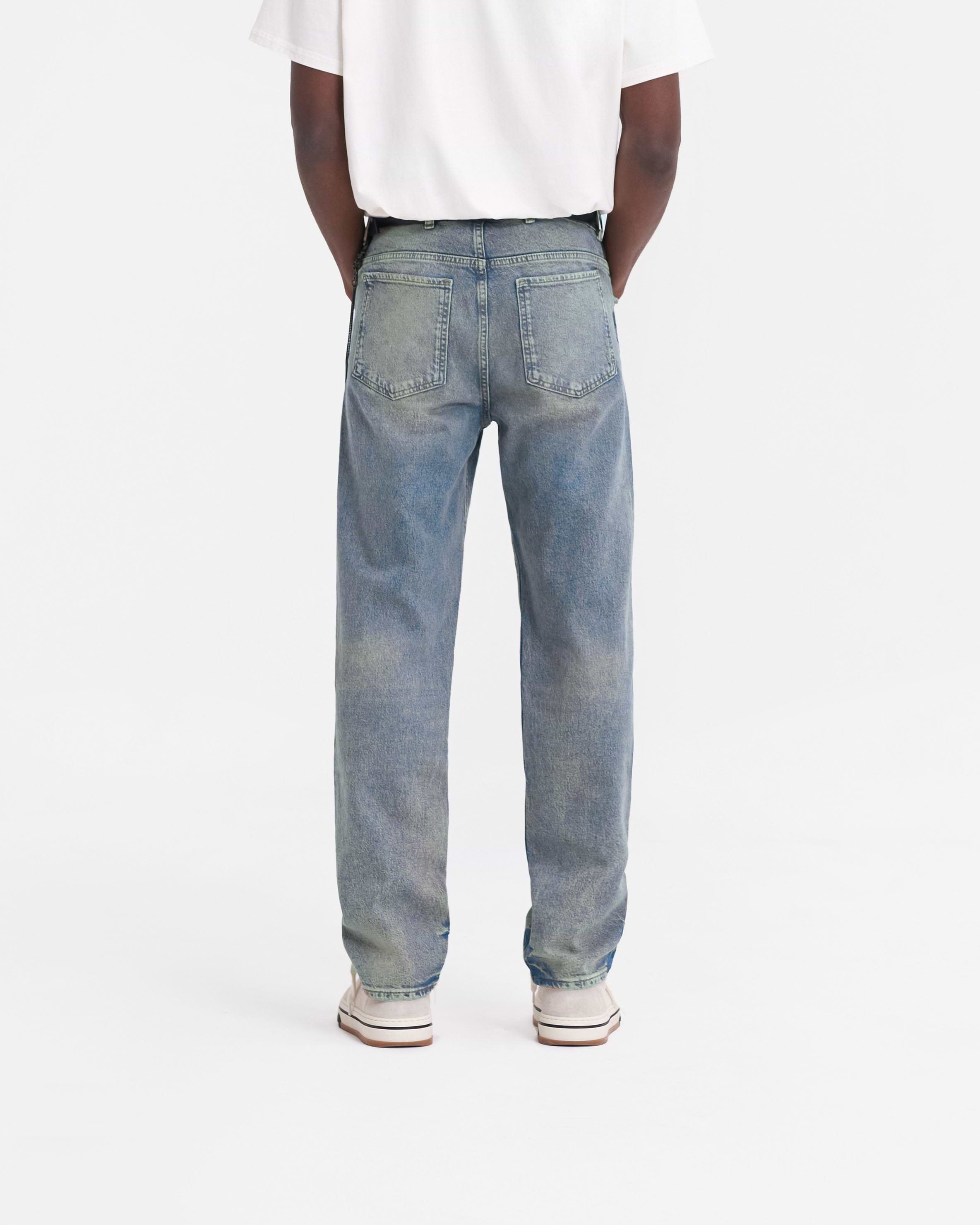 Man wearing blue straight leg jeans on a plain white background | R2 Straight Leg Denim in Blue Cream | Jeans with a zip fly and belt loops | FW23 Denim | Represent Clo