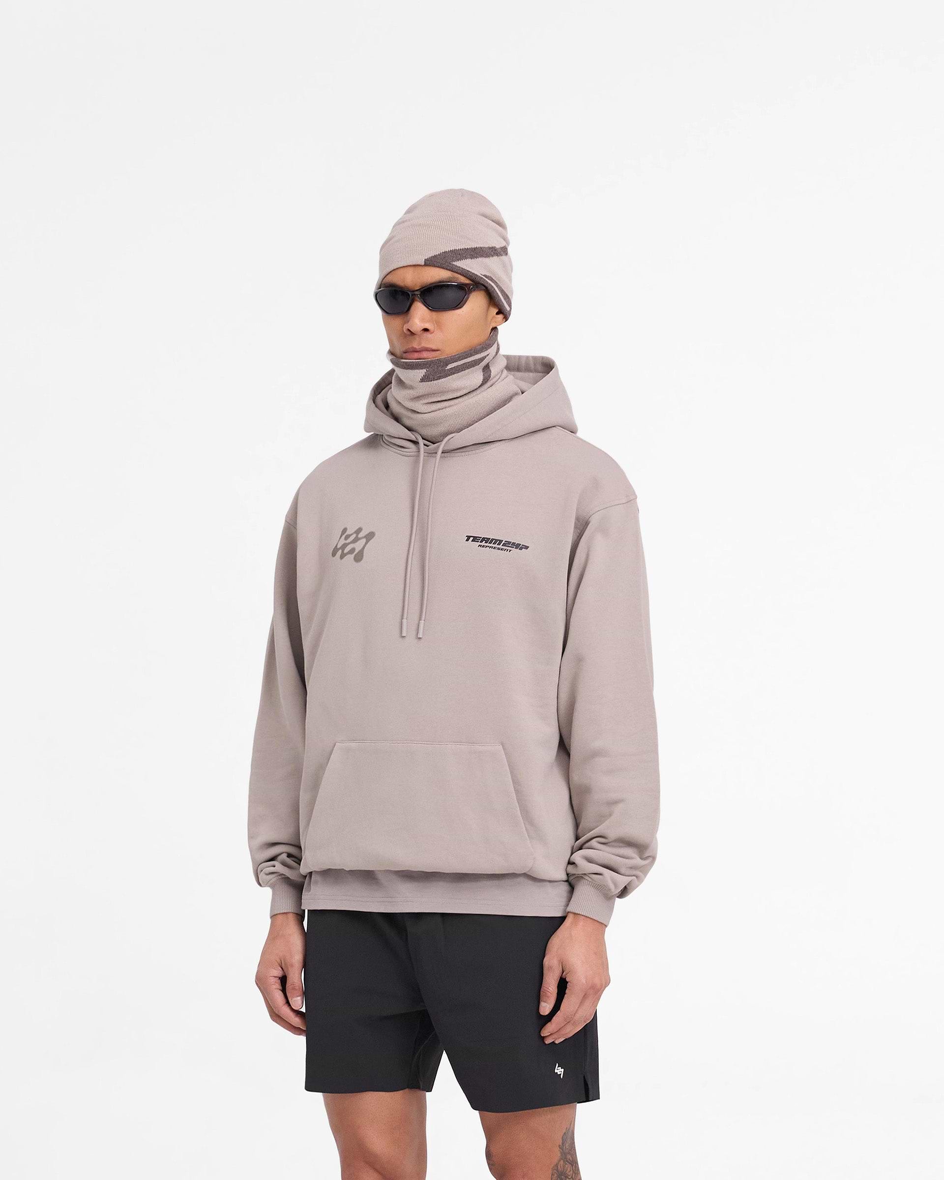 Man wearing an oversized grey hoodie on a plain white background | 247 Future Terrains Oversized Hoodie in Moonrock | Heavyweight cotton hoodie with ribbed hem and cuffs | 247 Hoodies | Represent Clo