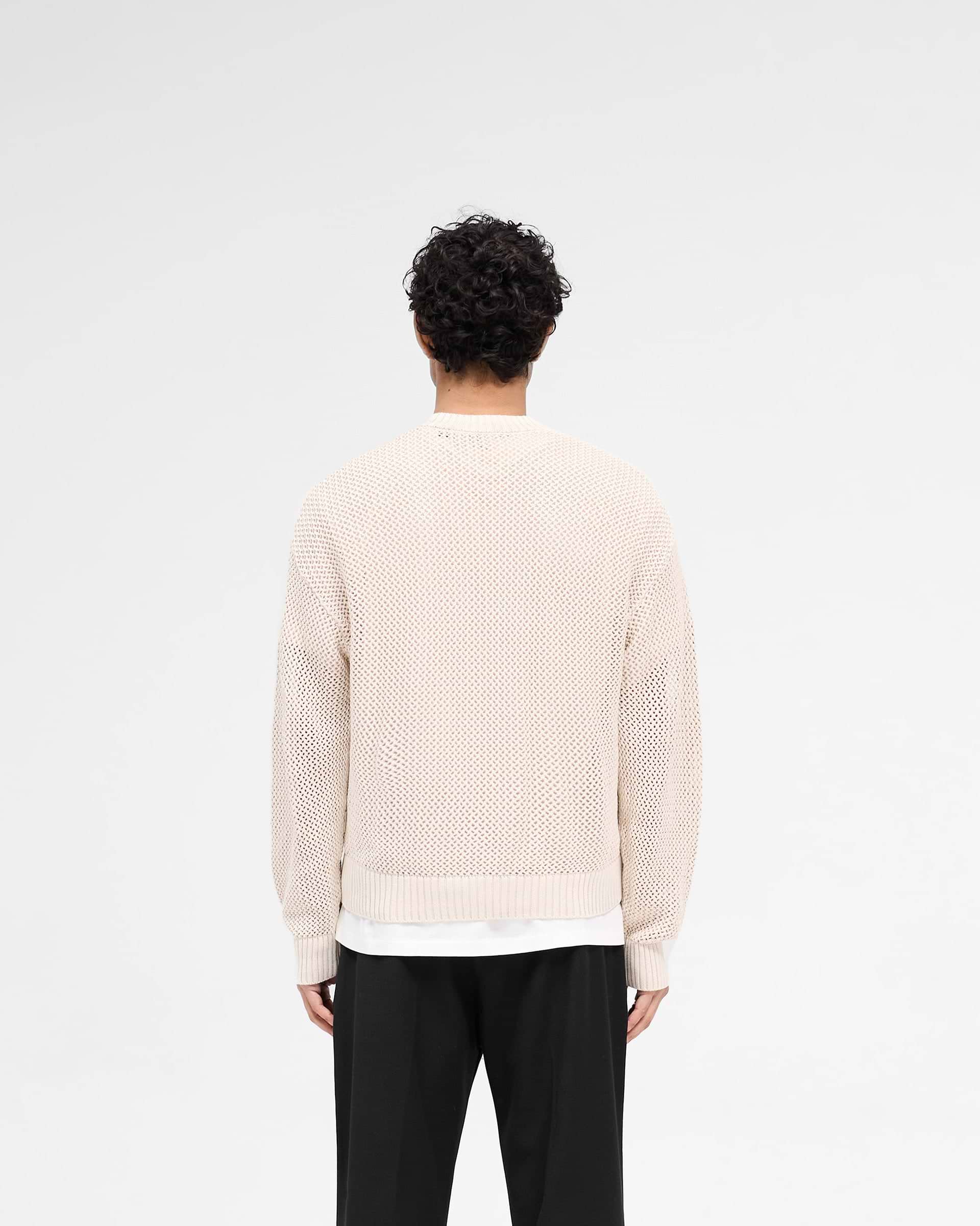 Man wearing an off white knit sweater on a plain white background | Open Gauge Knit Sweater in Off White | Slightly oversized open knit sweater | SS25 Knitwear | Represent Clo