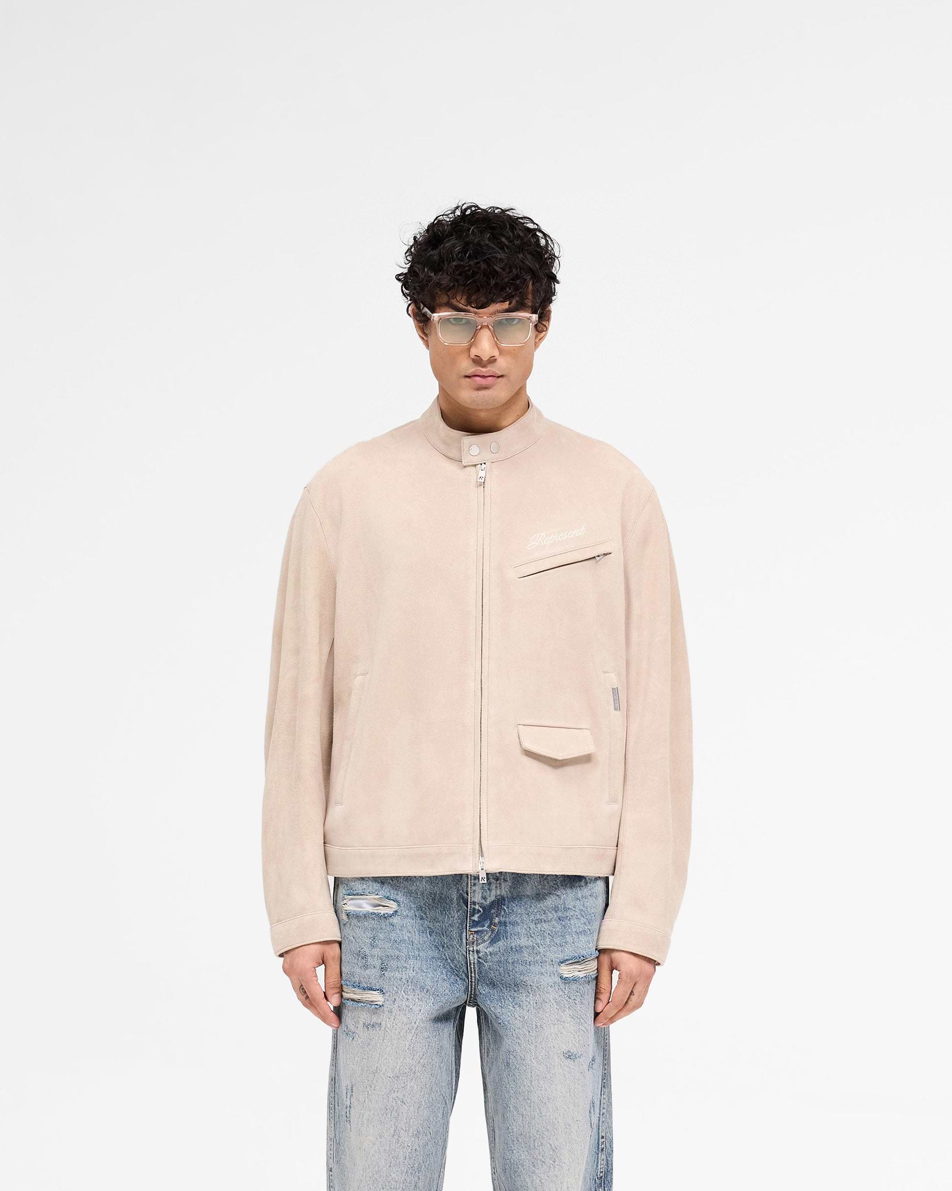 Man wearing a beige suede jacket on a plain white background | Overdrive Suede Jacket in Beige | Suede biker jacket with vented shoulders | SS25 Outerwear | Represent Clo