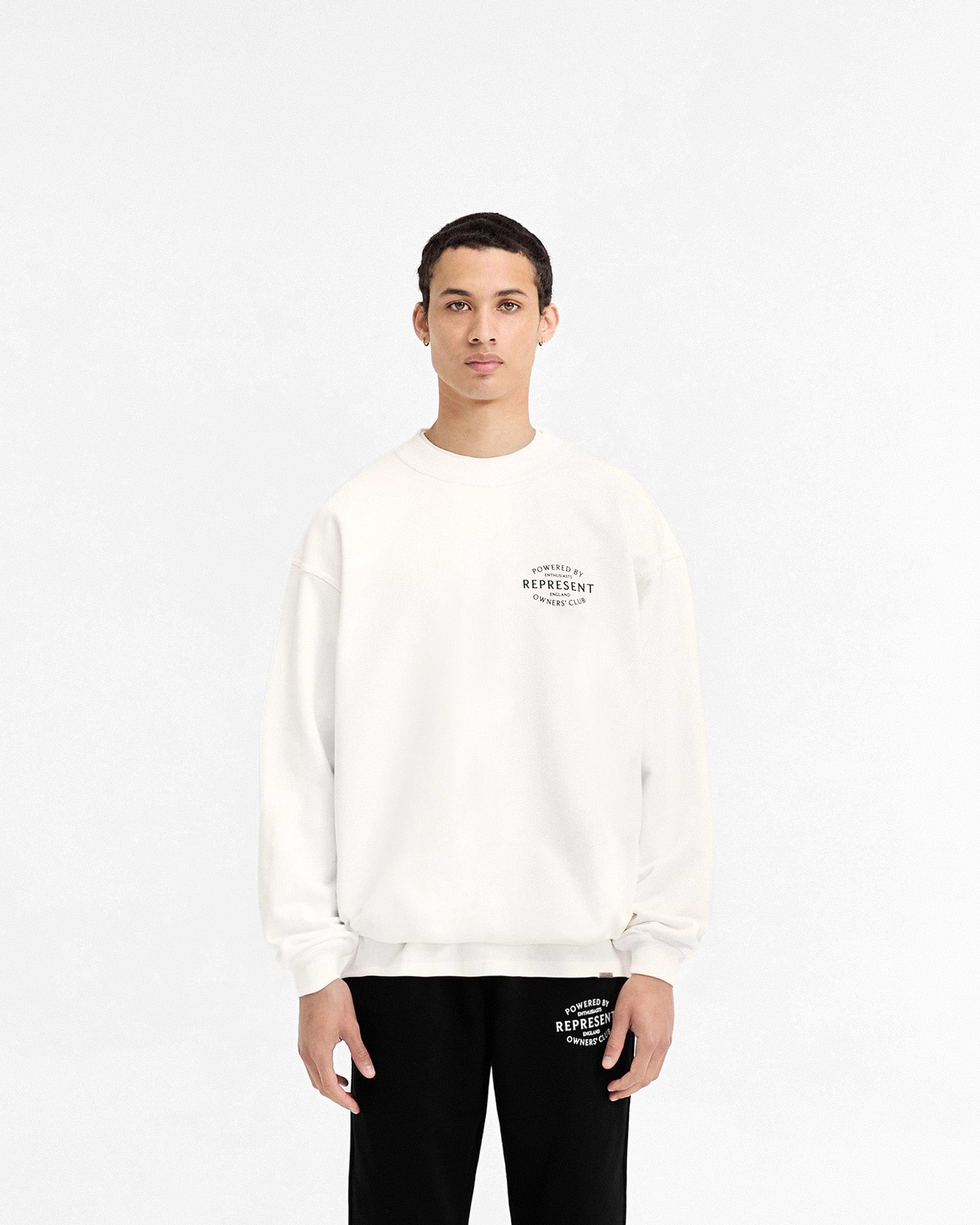 Man wearing a white sweater on a plain white background | Represent Owners Club Stamp Sweater in Flat White | Heavy weight jersey cotton oversized sweater | Owners Club Sweaters | Represent Clo
