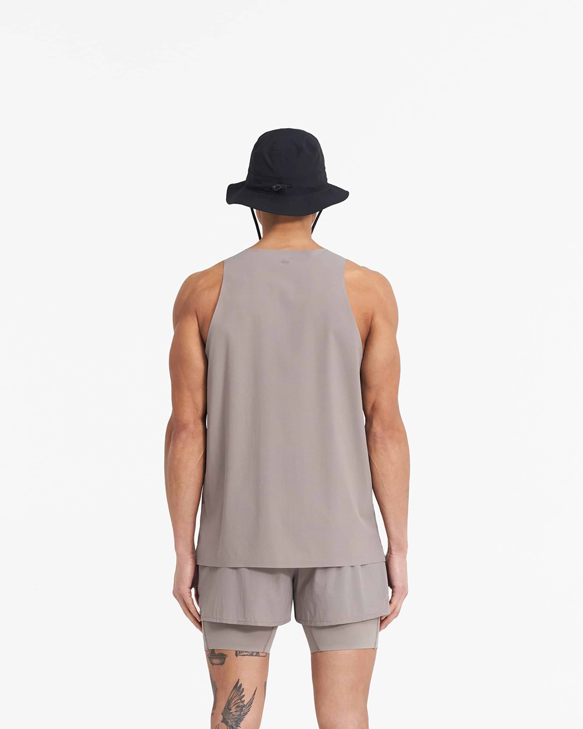 Man wearing a grey perforated training vest on a plain white background | 247 Singlet in Cinder | Stretch ripstop vest with bonded hems and flatlock seams | 247 T-Shirts | Represent Clo
