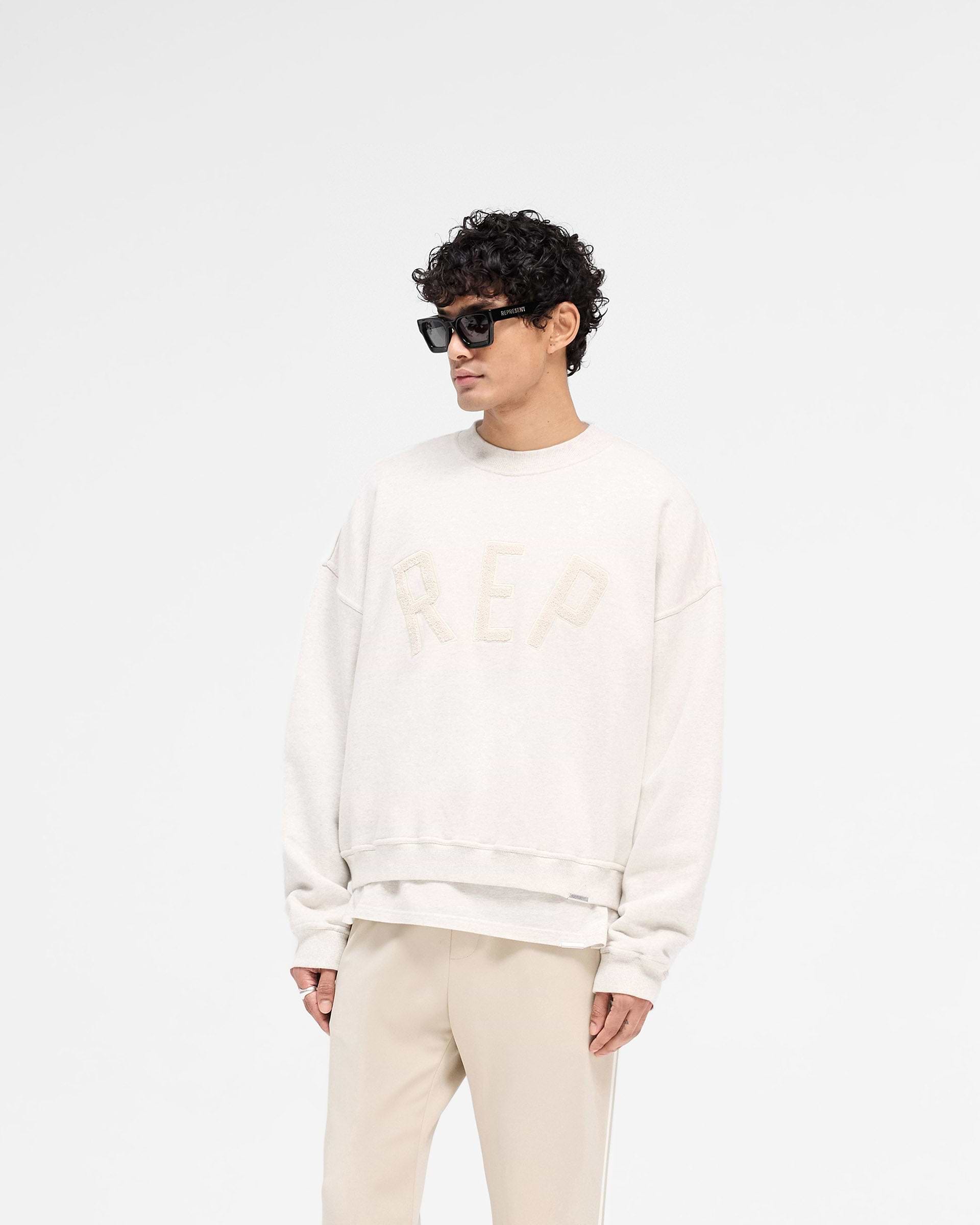 Back product image of a mens cream sweater on a plain white background | Rep Applique Sweater in Cream Marl | Boxy fit cotton sweater with textured Rep applique | SS25 Sweaters | Represent Clo