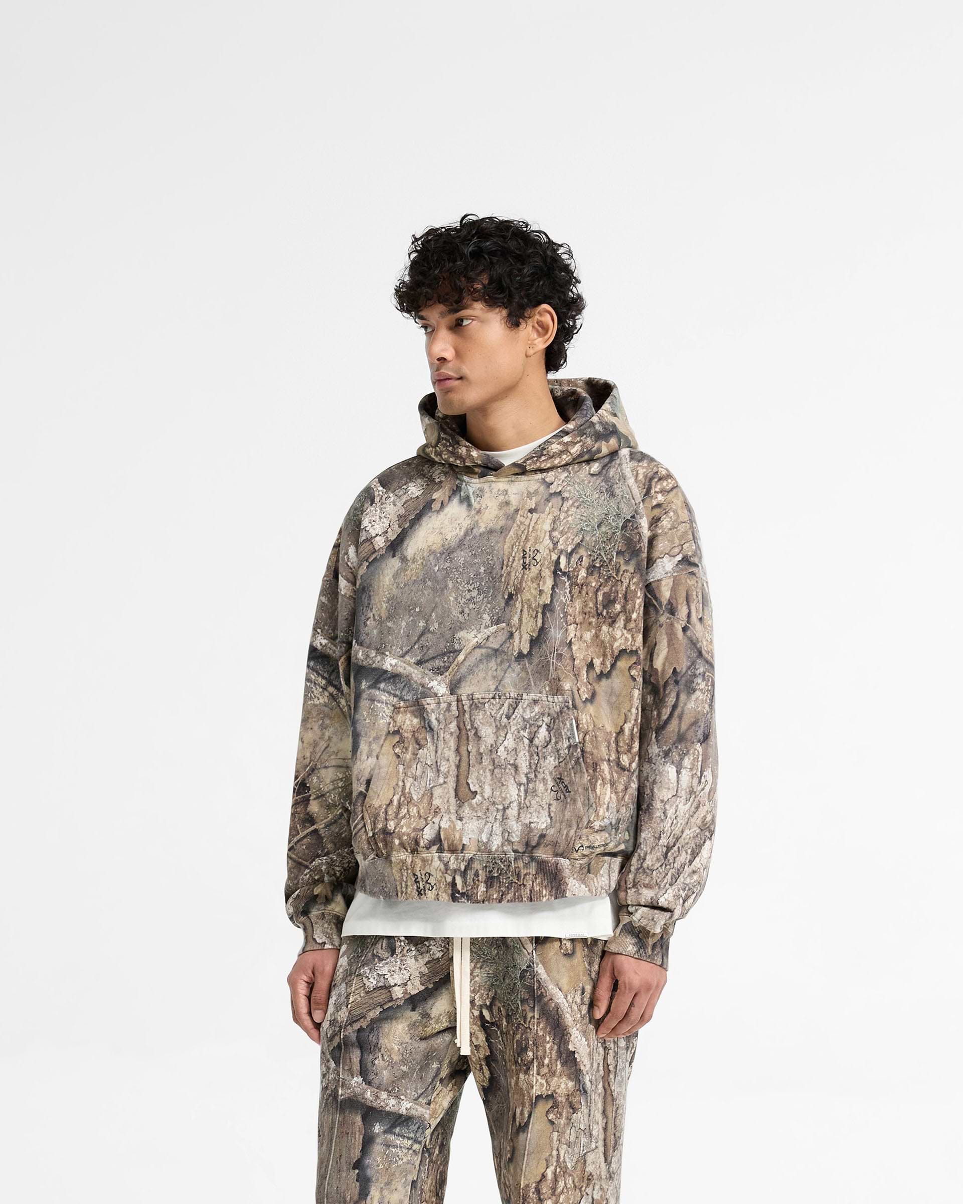 Back product image of a mens camo hoodie on a plain white background | Realtree Camo Boxy Hoodie in Camo | Heavyweight cotton boxy fit camo hoodie with ribbed cuffs and hem | SS25 Hoodies | Represent Clo