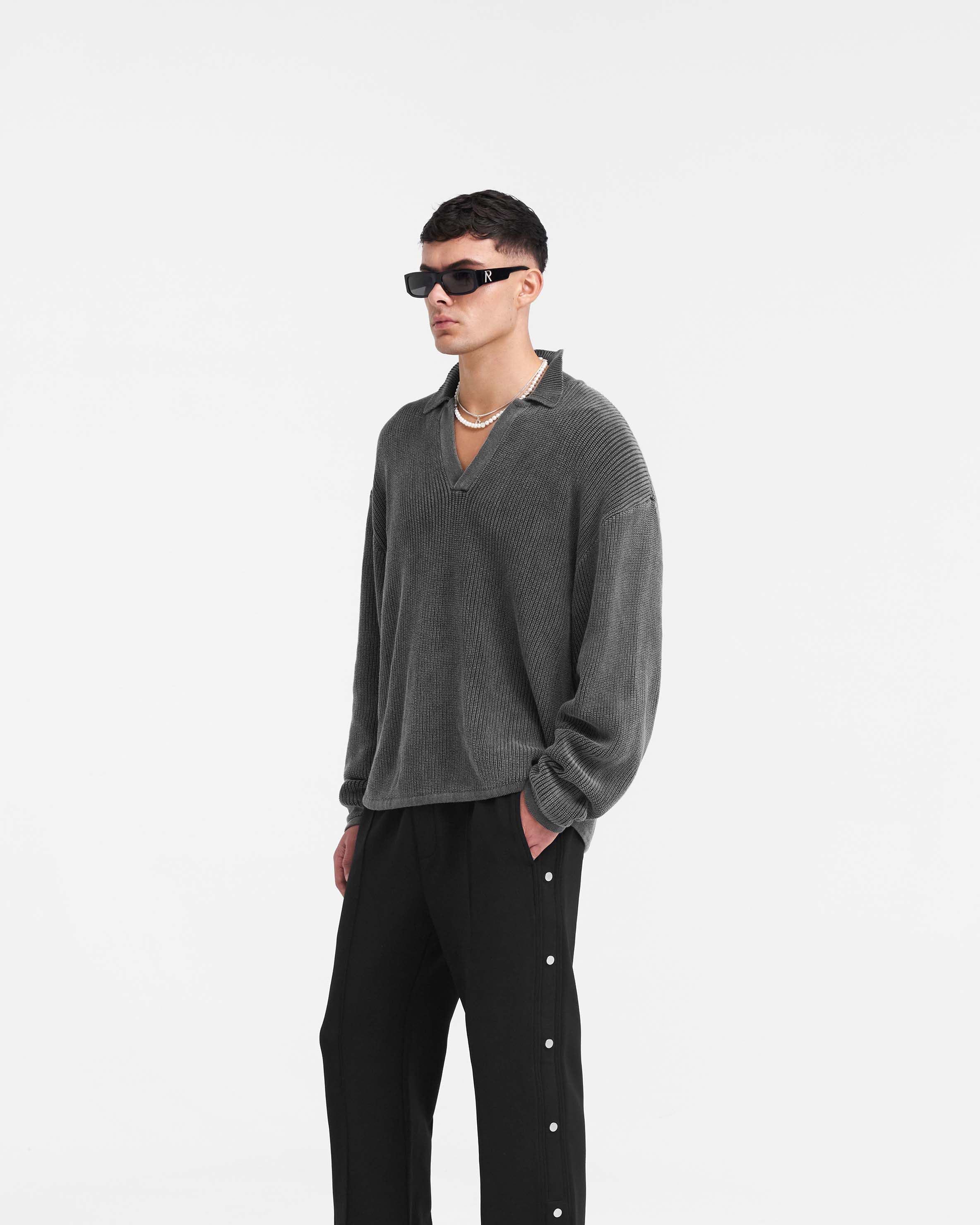 Man wearing a black oversized knit polo on a plain white background | Ribbed Knit Oversized Polo in Washed Black | 100% cotton knitwear with open neck | PRE SS24 Knitwear | Represent Clo