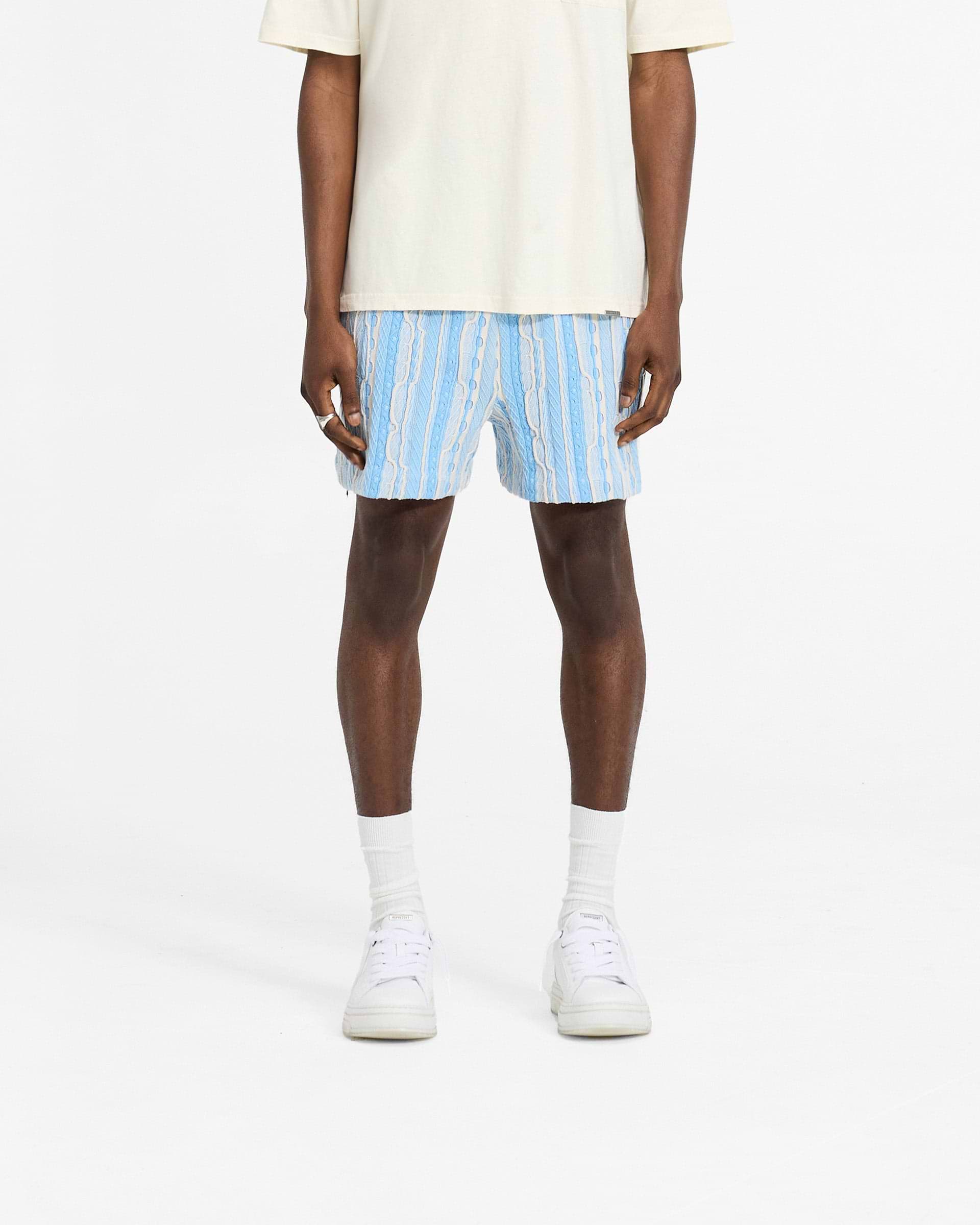 Man wearing relaxed fit blue shorts with elasticated waistband on a plain white background | Mixed Knit Shorts in Royal Blue | Custom knit pattern shorts | SC24 Shorts | Represent Clo