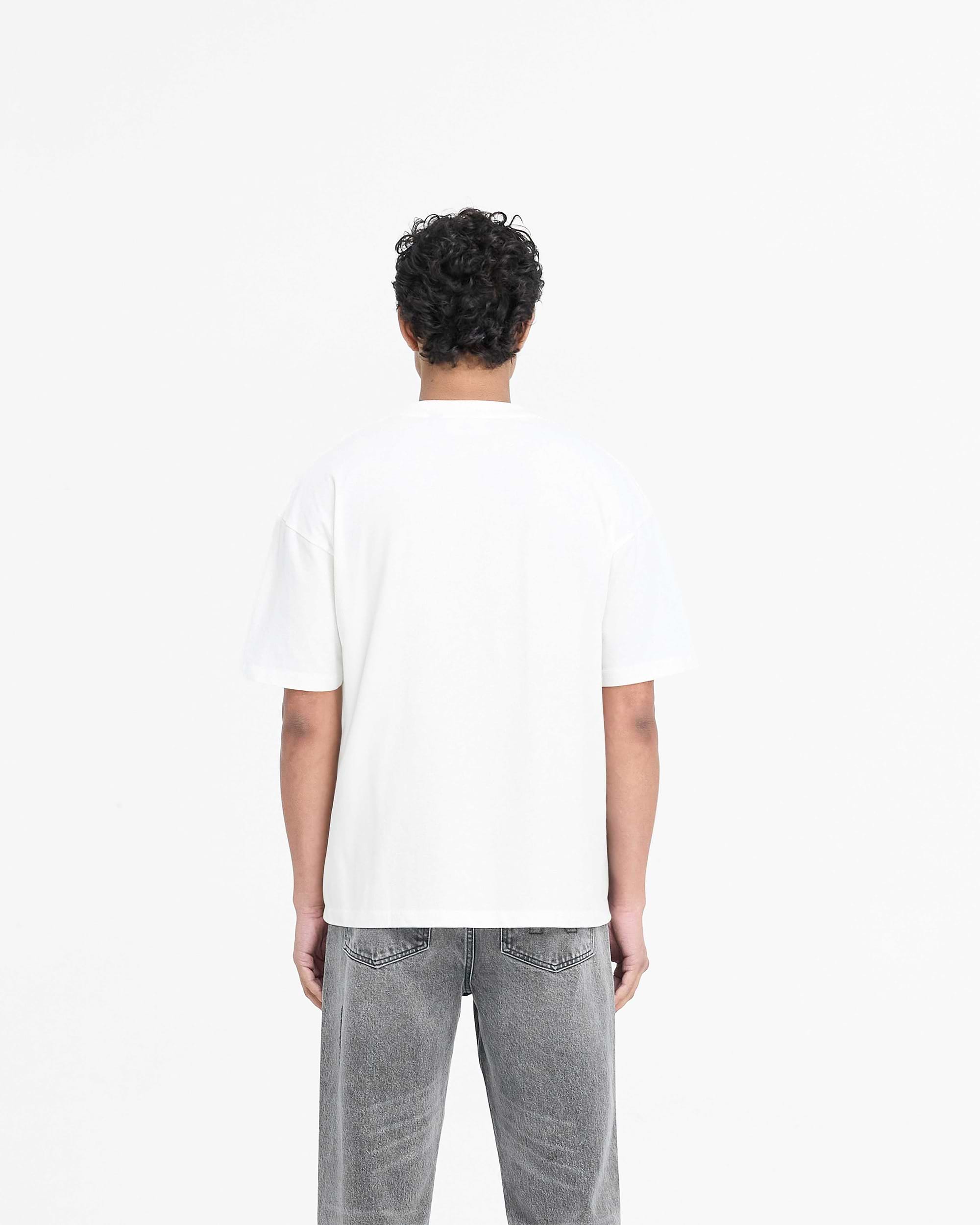 Man wearing a slightly oversized white t-shirt on a plain white background | Block Logo T-Shirt in Flat White | Super soft cotton with metal branding | PRE SS25 T-Shirts | Represent Clo