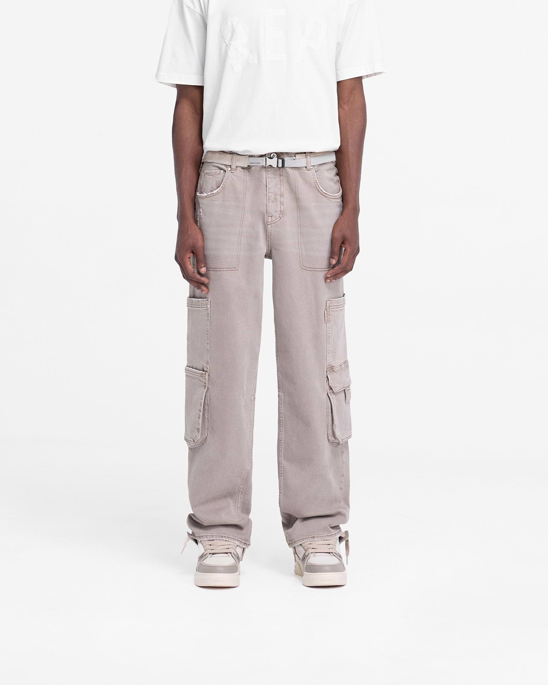 Man wearing stone denim jeans on a plain white background | R3 Workshop Denim in Stone | Baggy fit jeans with double leg pockets | FW24 Denim | Represent Clo