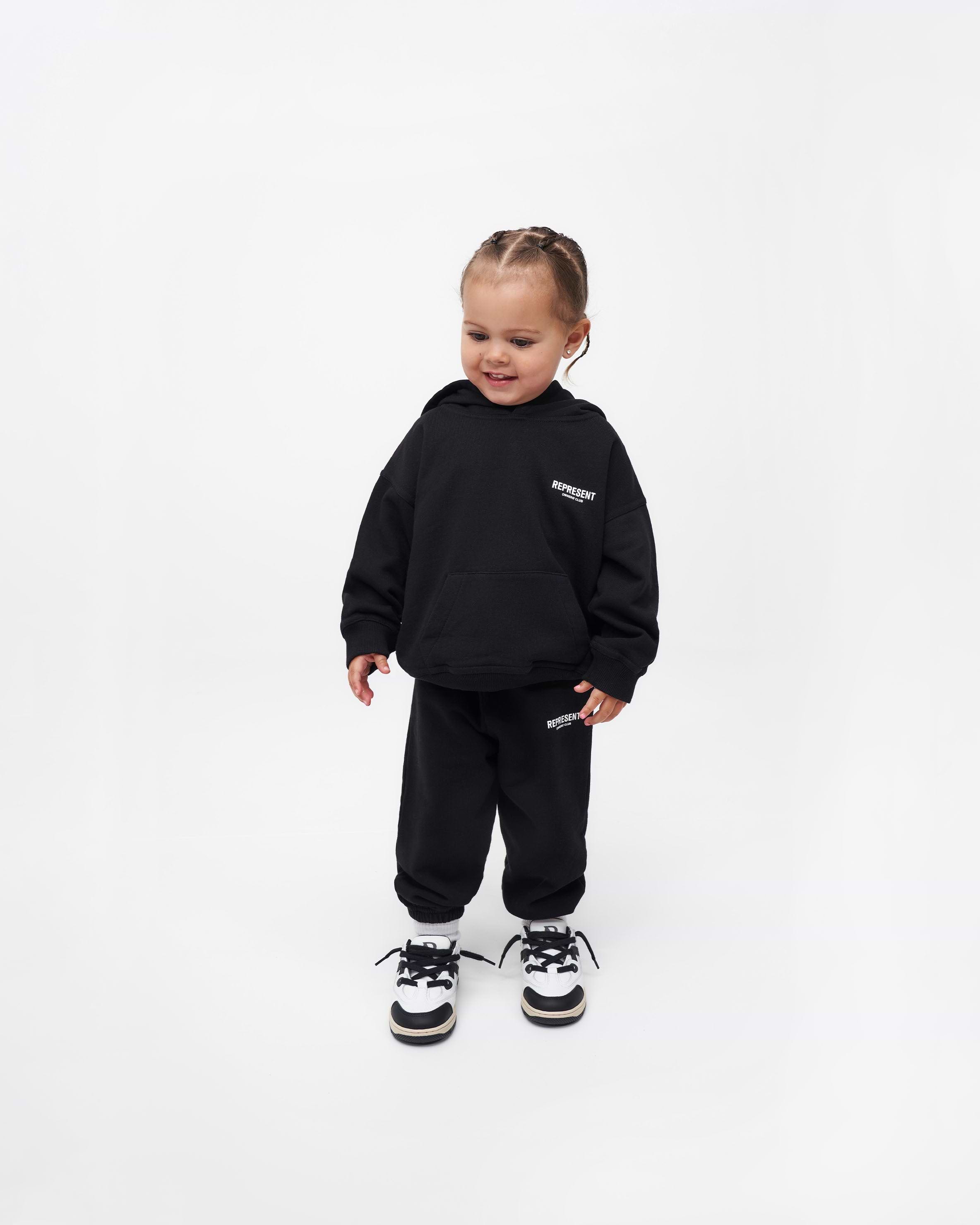 Back product image of a kids black sweatpants on a plain white background | Represent Mini Owners Club Sweatpants in Black | Kids joggers with elasticated waistband and cuffs | Owners Club Pants | Represent Clo