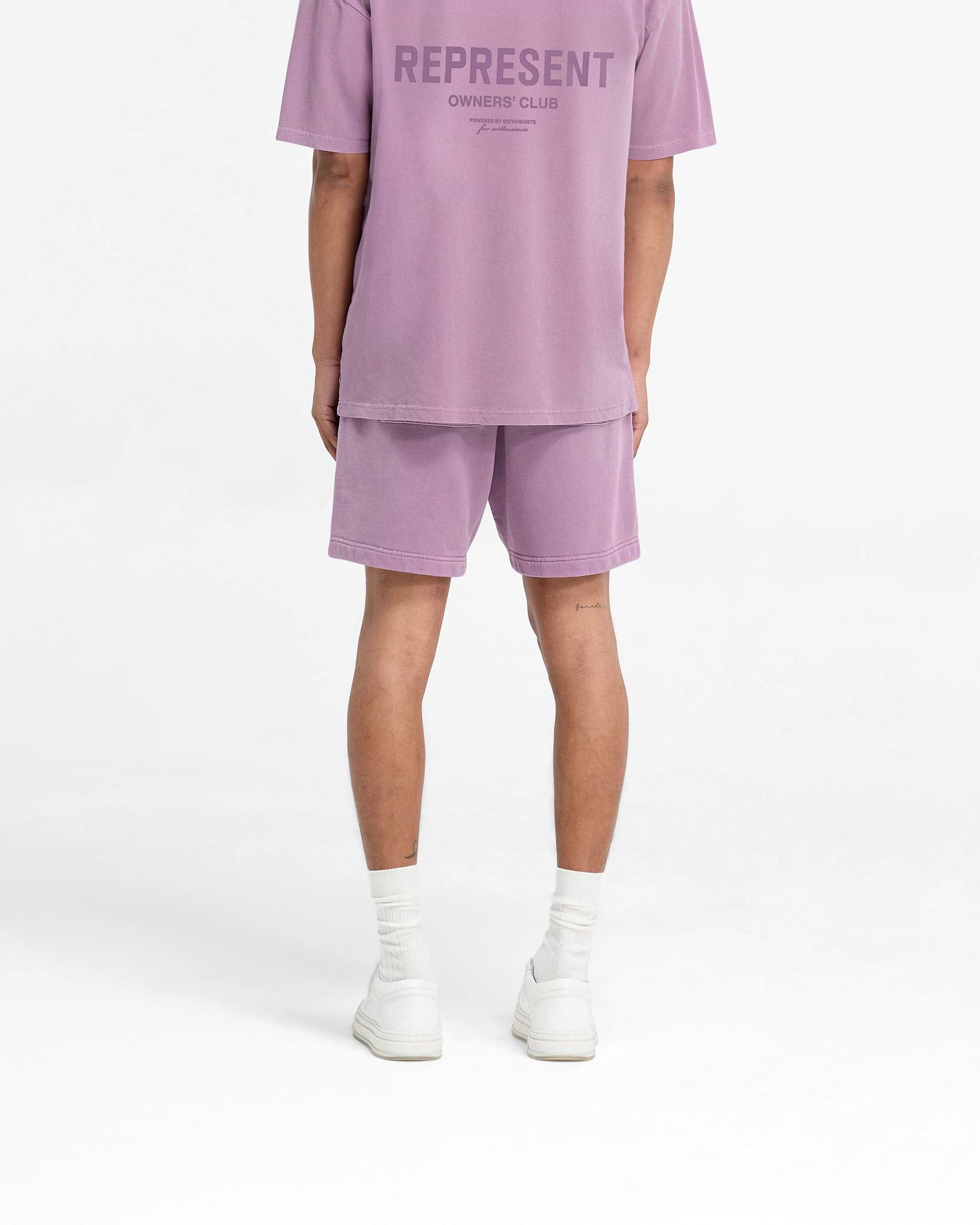 Man wearing mid purple shorts on a plain white background | Represent Owners Club Shorts in Mid Purple | Relaxed fit shorts with elasticated waistband | Owners Club Shorts | Represent Clo