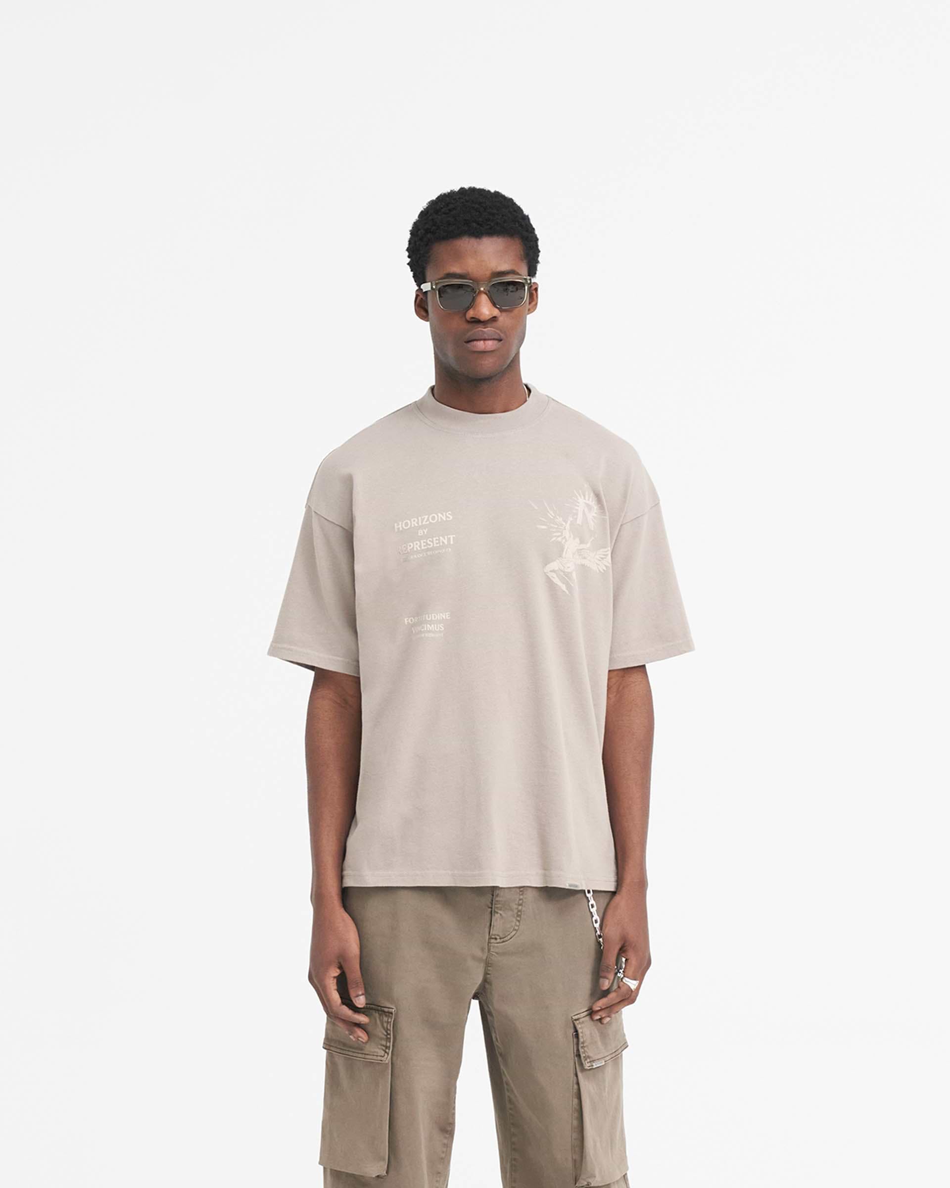 Man wearing an oversized taupe t-shirt on a plain white background | Icarus T-Shirt in Taupe | Medium weight cotton t-shirt with Icarus graphic | SS24 T-Shirts | Represent Clo