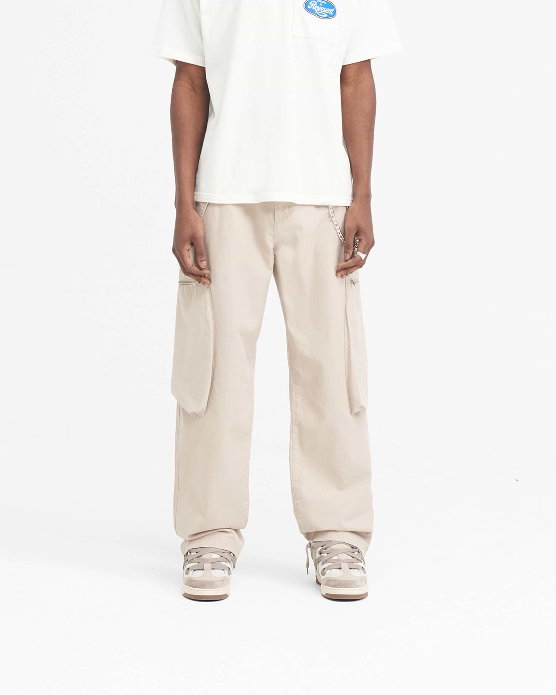 Man wearing cashmere coloured pants on a plain white background | Workshop Pant in Cashmere | Oversized fit pants with 3D back pockets | SS24 Pants | Represent Clo