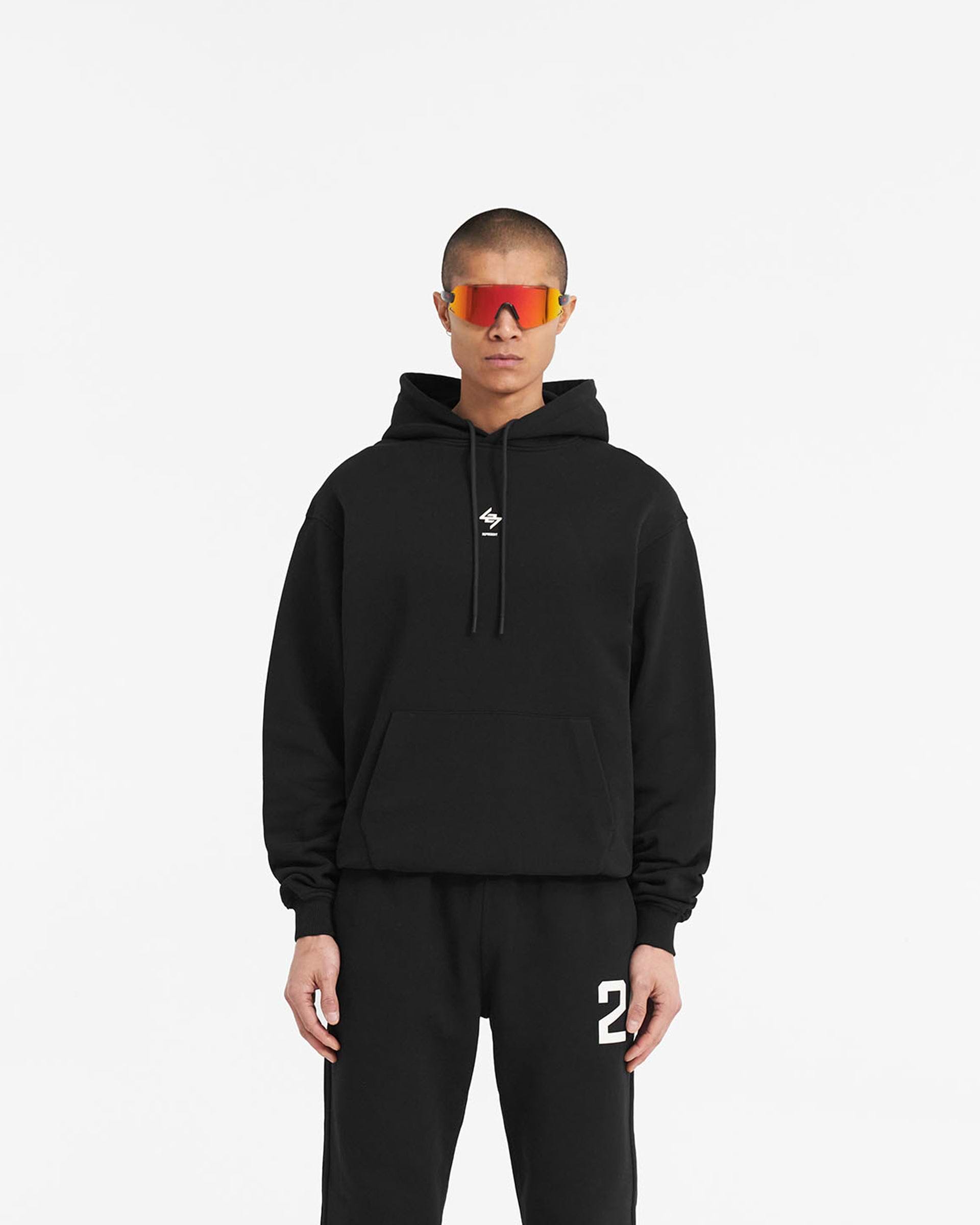 Man wearing a black oversized hoodie on a plain white background | 247 Oversized Hoodie in Jet Black | Oversized fit with 247 branding | 247 Hoodies | Represent Clo