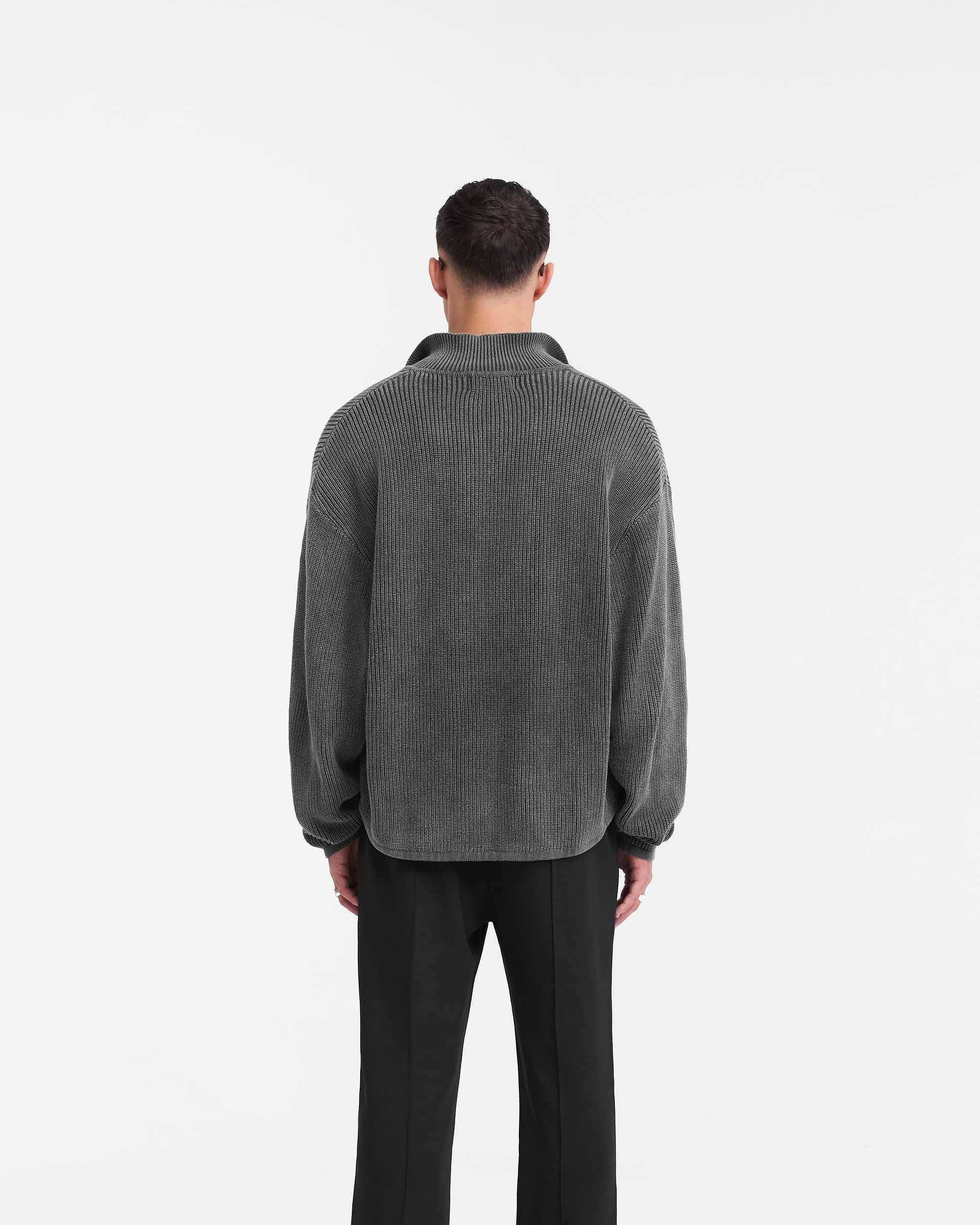 Man wearing a black ribbed knit polo on a plain white background | Ribbed Knit Oversized Polo in Washed Black | Oversized knit polo with open neck and loose hem | PRE SS24 Knitwear | Represent Clo