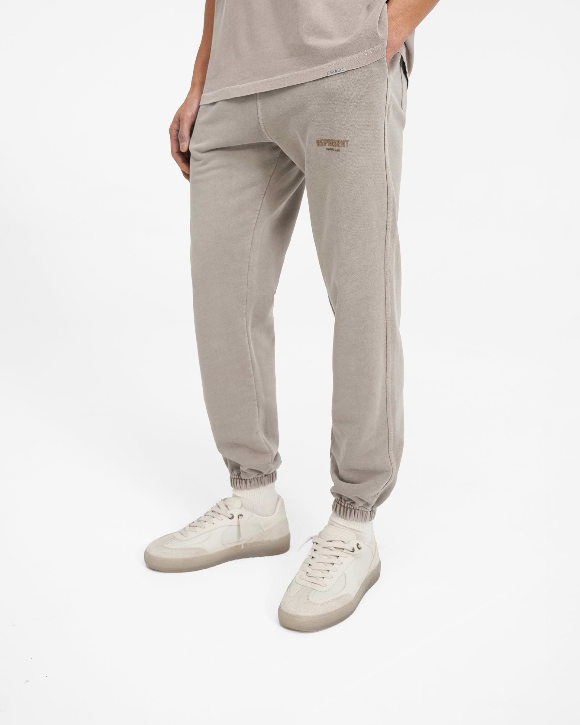 Man wearing grey sweatpants on a plain white background | Represent Owners Club Sweatpant in Mushroom | Sweatpants with elasticated waistband and pockets | Owners Club Pants | Represent Clo