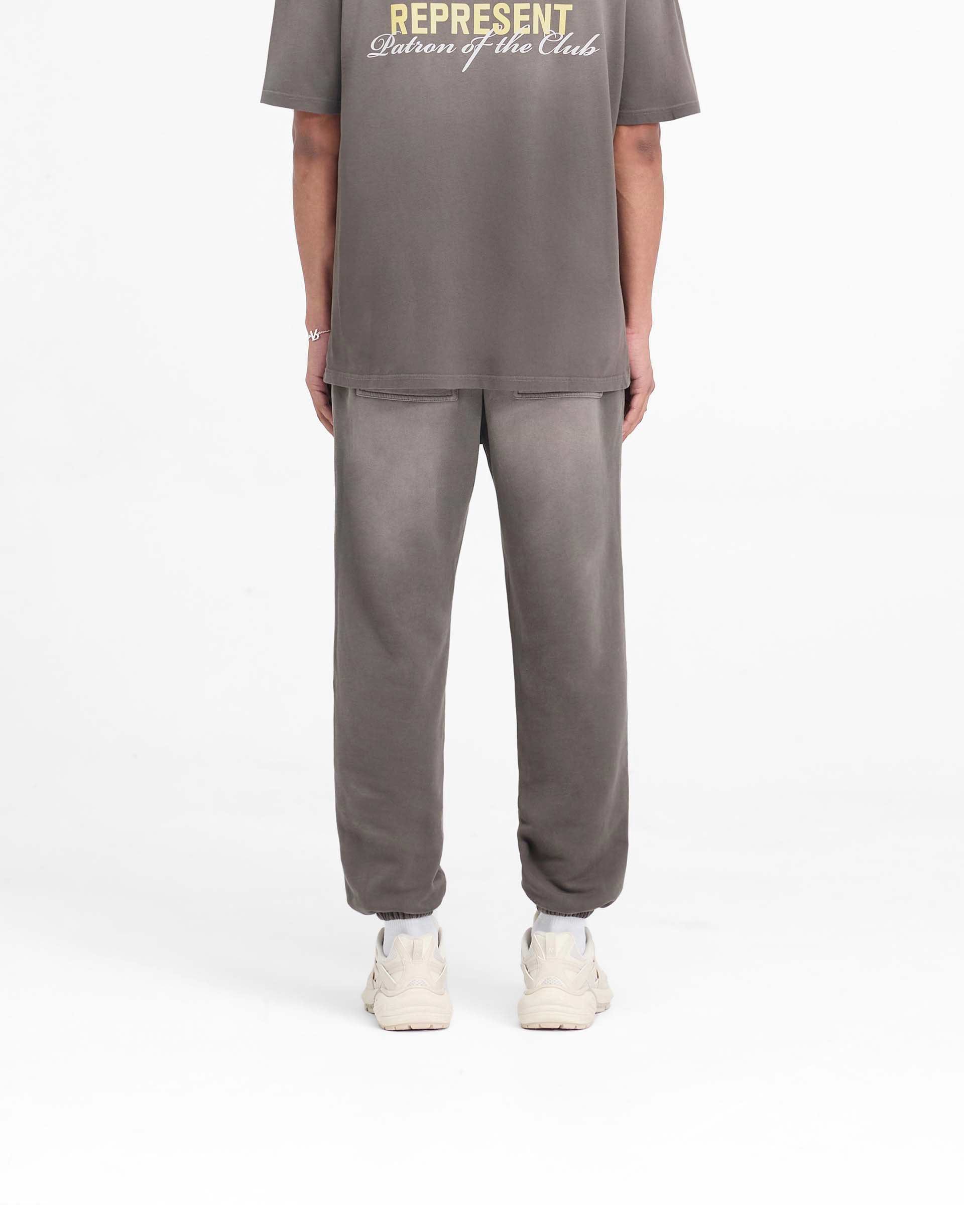 Man wearing relaxed fit washed olive sweatpants on a plain white background | Patron Of The Club Sweatpant in Washed Olive | Heavyweight cotton sweatpants with elasticated waistband and cuffs | Patrons Pants | Represent Clo