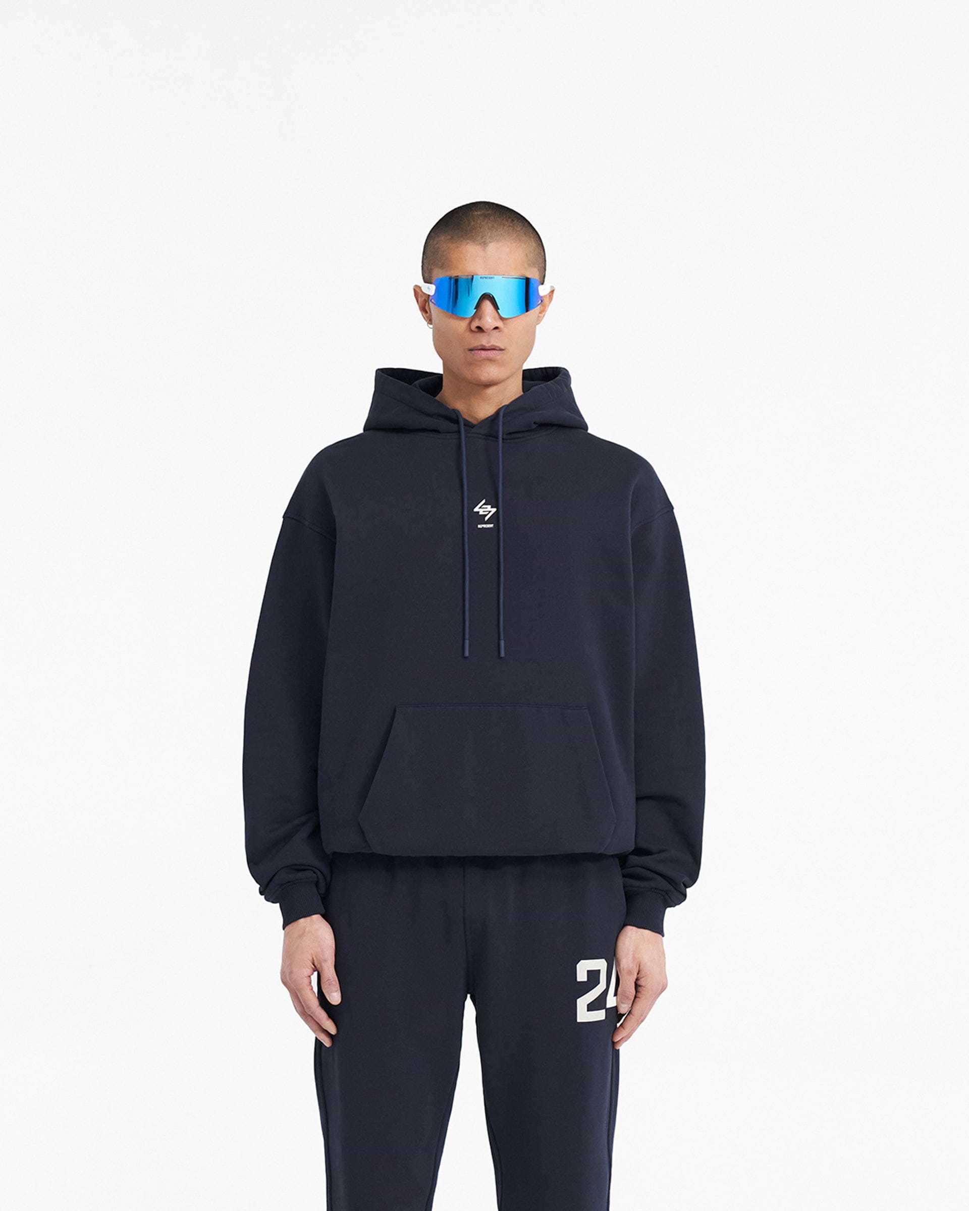 Man wearing a navy hoodie on a plain white background | 247 Oversized Hoodie in Navy | Oversized hoodie with ribbed cuffs and hem | 247 Hoodies | Represent Clo