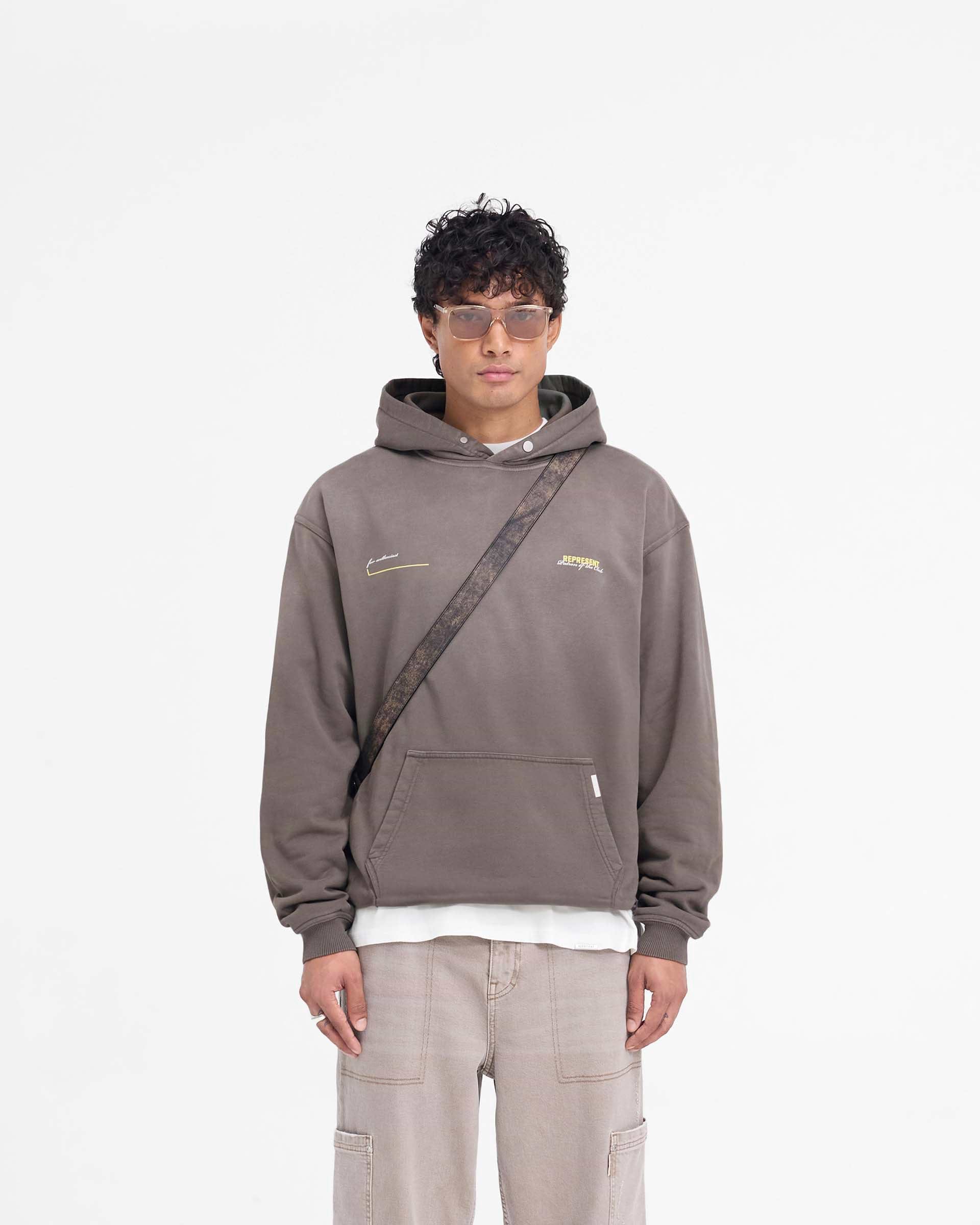 Man wearing an oversized olive hoodie on a plain white background | Patron Of The Club Hoodie in Washed Olive | Oversized hoodie with Patron of the Club print | Patrons Hoodies | Represent Clo