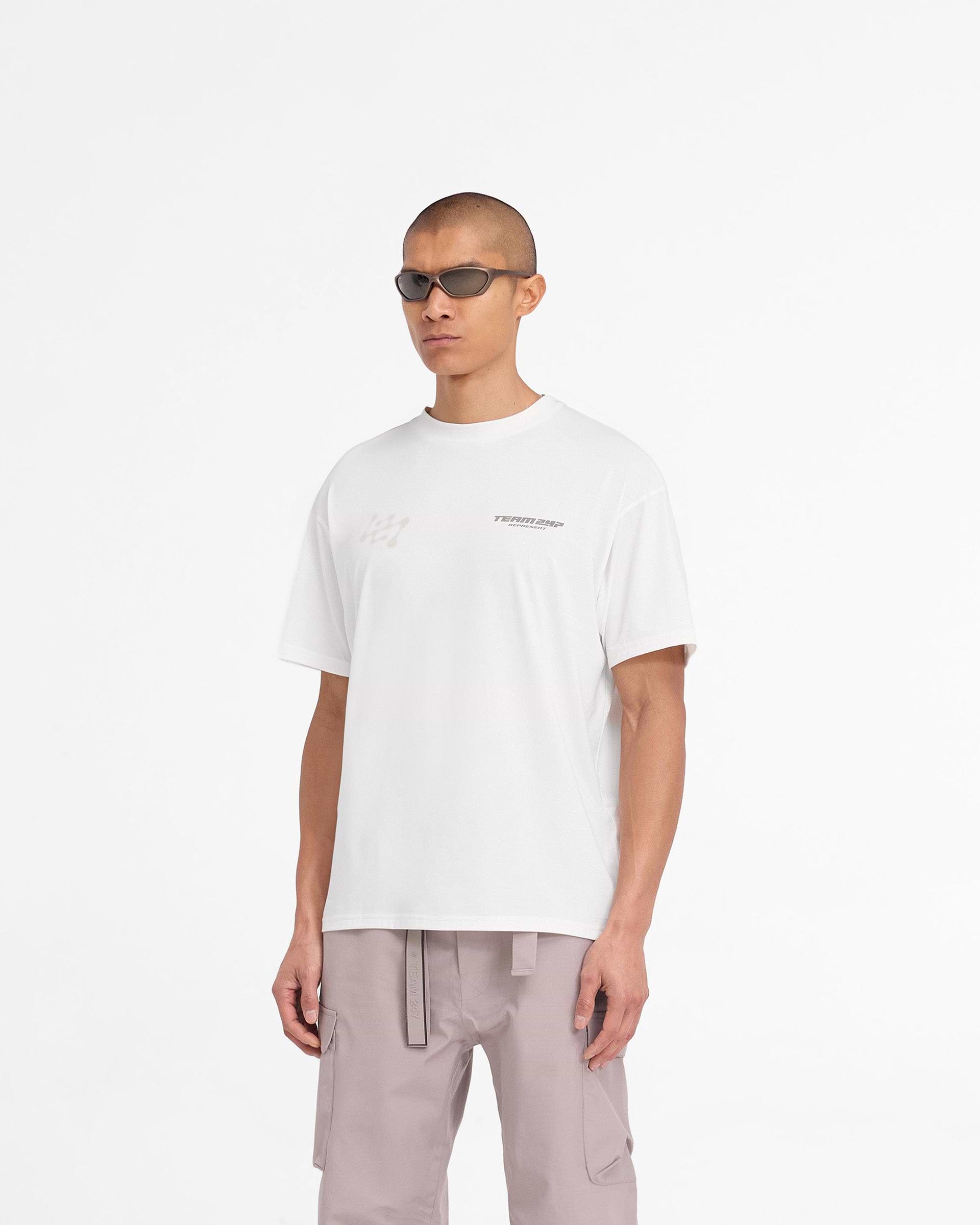 Man wearing an oversized white t-shirt on a plain white background | 247 Future Terrains Oversized T-Shirt in Flat White | Lightweight training t-shirt with quick-dry fabric | 247 T-Shirts | Represent Clo