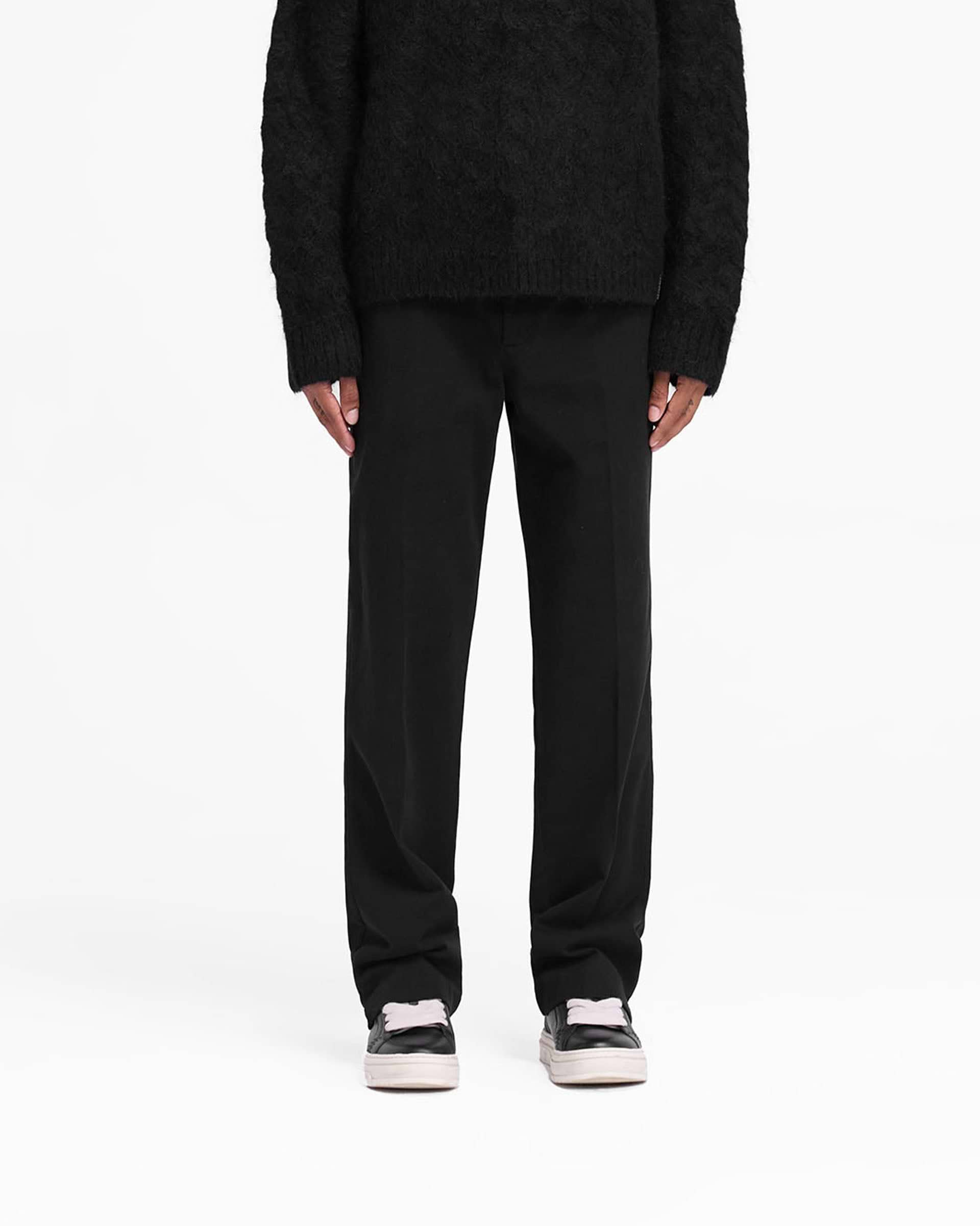 Man wearing black cotton pants on a plain white background | Cotton Pant in Black | Straight leg cotton twill pants with side split | FW24 Pants | Represent Clo