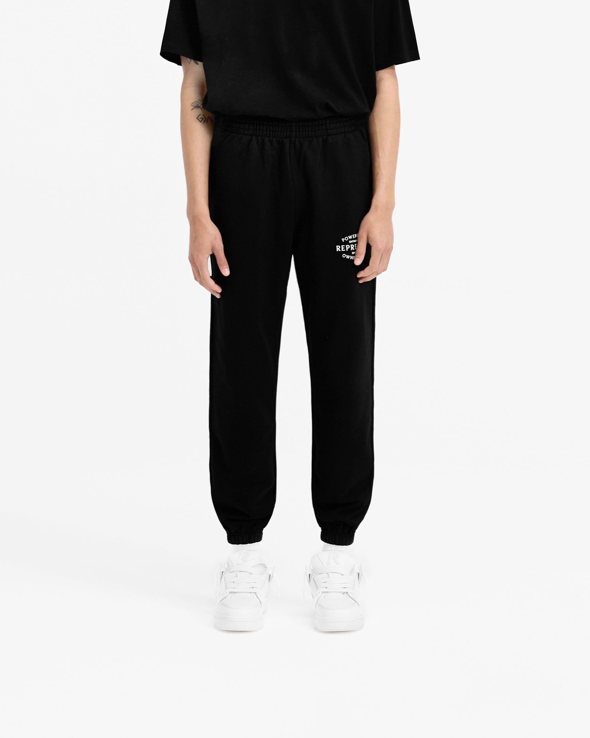 Man wearing black sweatpants on a plain white background | Owners Club Stamp Sweatpant in Jet Black | Sweatpants with elasticated waistband and cuffs | Owners Club Pants | Represent Clo