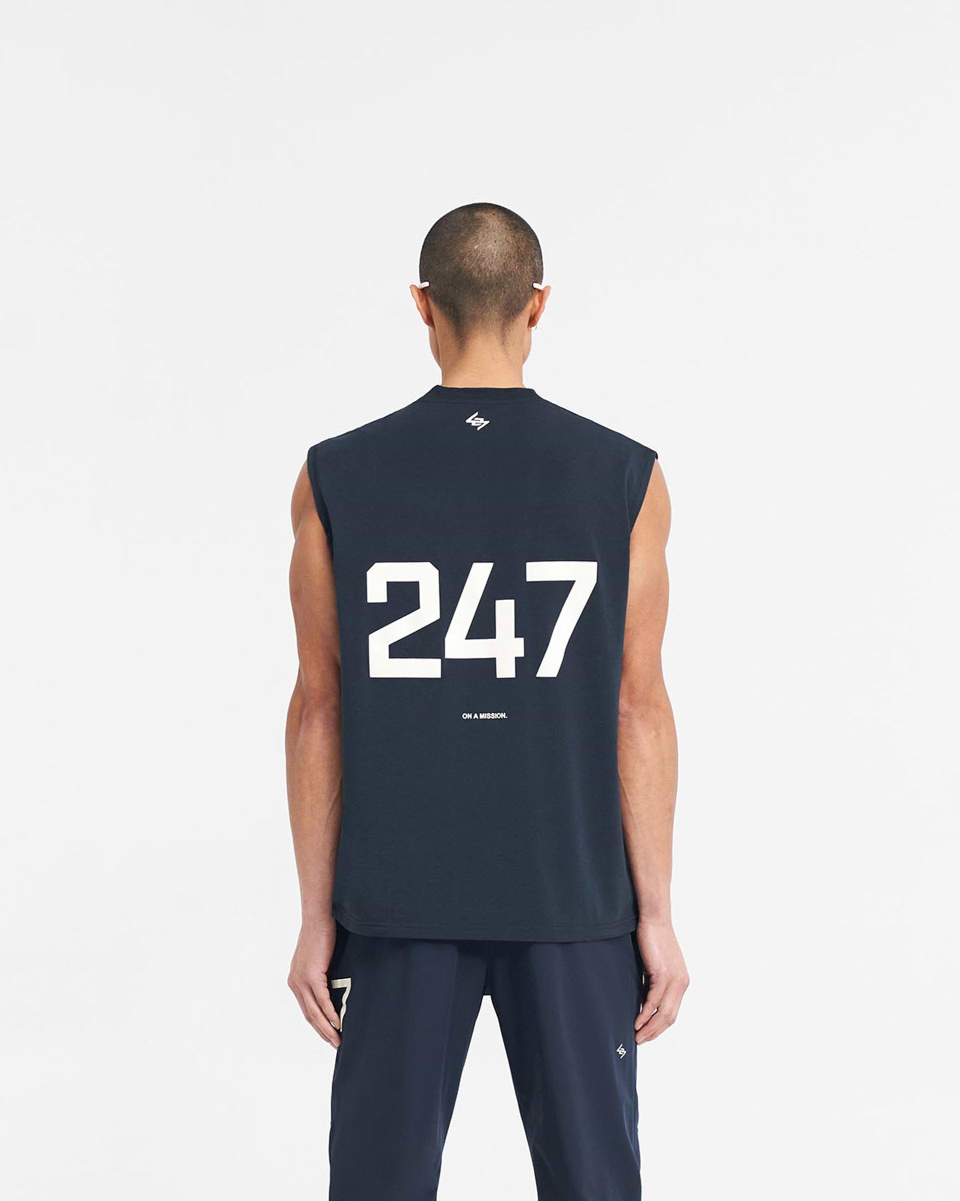 Man wearing a navy tank top on a plain white background | 247 Oversized Tank in Navy | Lightweight breathable tank top with 4-way stretch | 247 T-Shirts | Represent Clo