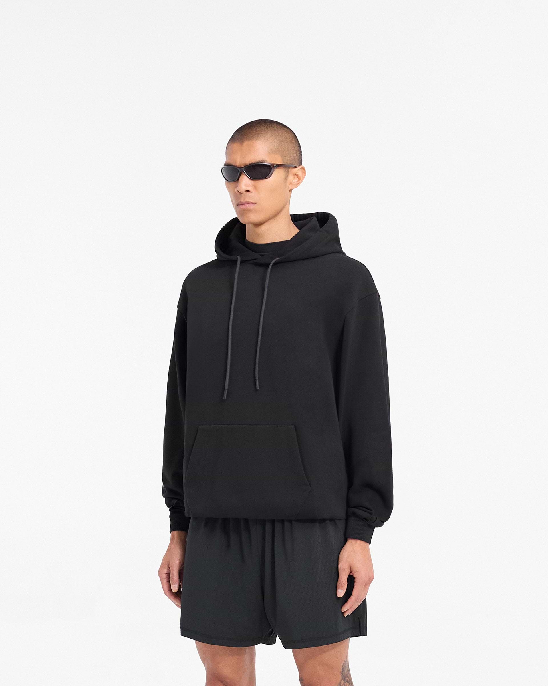Man wearing a black oversized hoodie on a plain white background | 247 DNA Oversized Hoodie in Black | Oversized hoodie with ribbed hem and cuffs | 247 Hoodies | Represent Clo