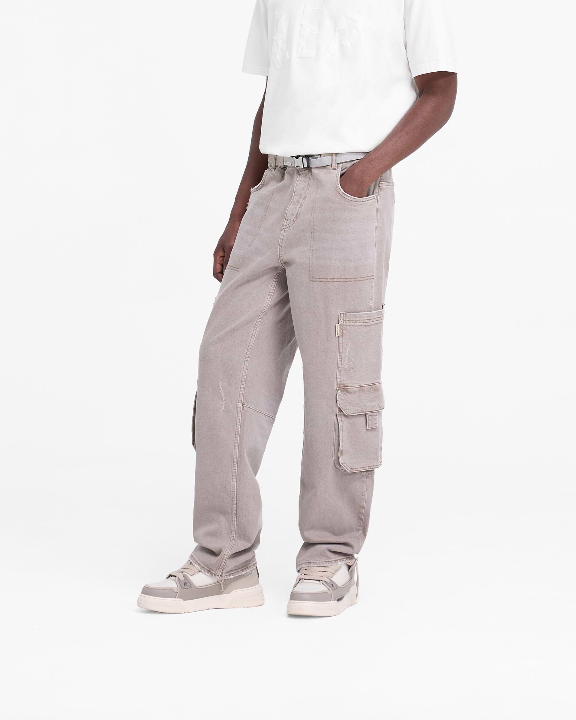 Man wearing stone denim jeans on a plain white background | R3 Workshop Denim in Stone | Baggy fit jeans with double leg pockets and removed back pocket | FW24 Denim | Represent Clo