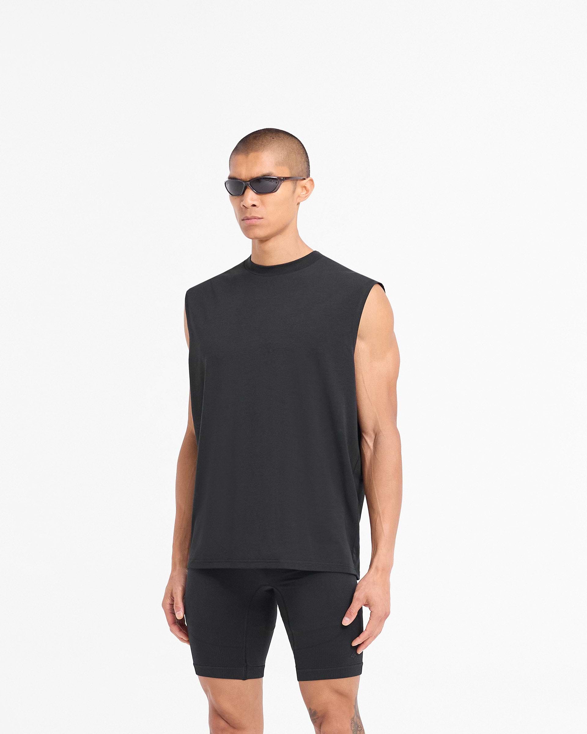 Man wearing a black tank top on a plain white background | 247 DNA Oversized Tank in Black | Lightweight breathable oversized fit gym tank top | 247 T-Shirts | Represent Clo