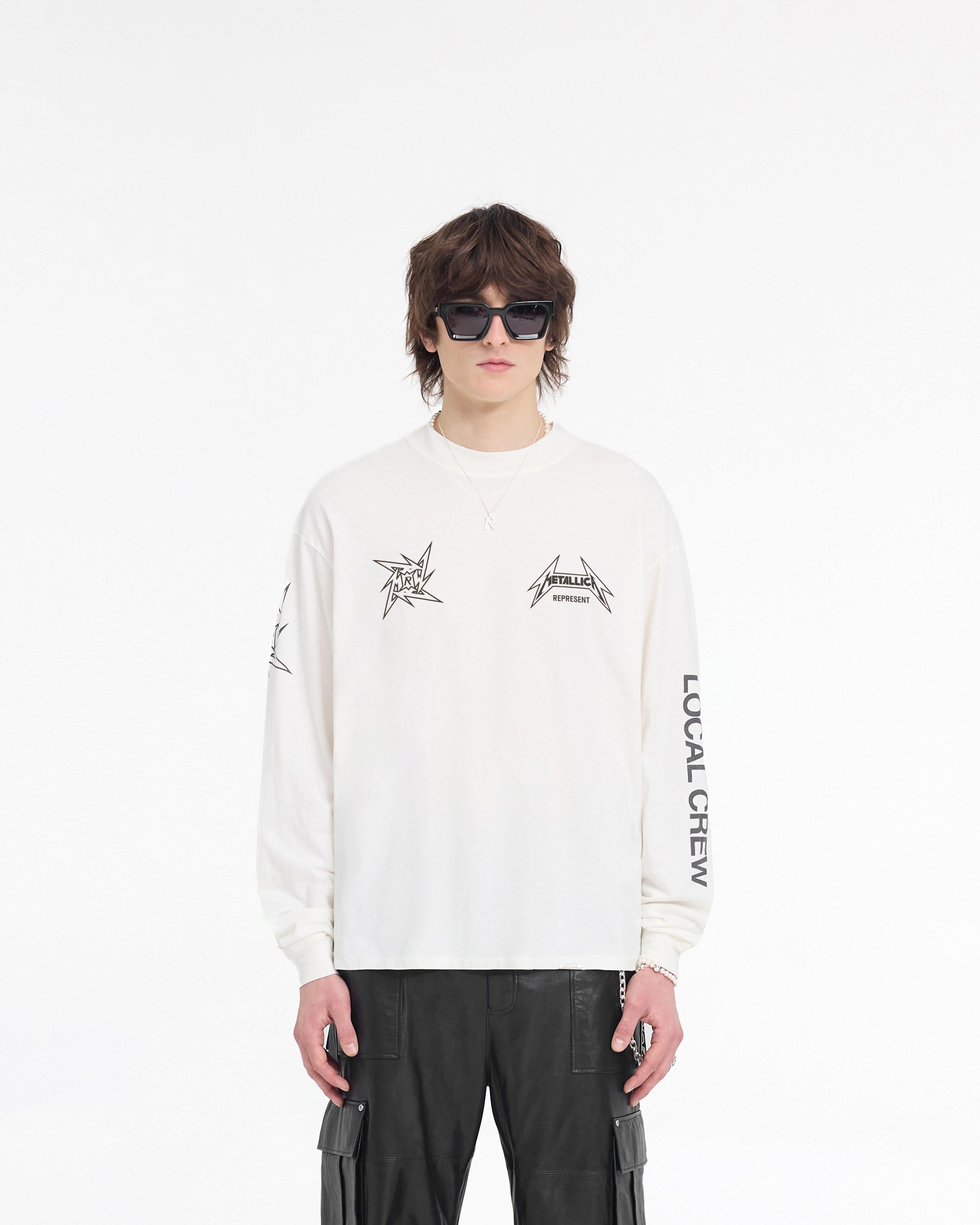 Man wearing a white long sleeve t-shirt on a plain white background | Represent X Metallica Local Crew Long Sleeve T-Shirt in Flat White | Slightly oversized t-shirt with vintage detailing | SS24 T-Shirts | Represent Clo