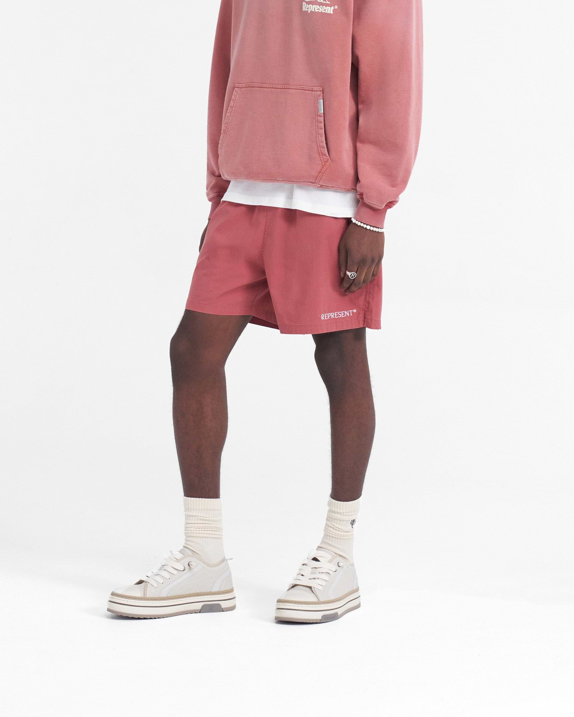 Back product image of mens orange shorts on a plain white background | Represent Short in Sunrise | Lightweight shorts with elasticated waistband and side seam pockets | SS24 Shorts | Represent Clo