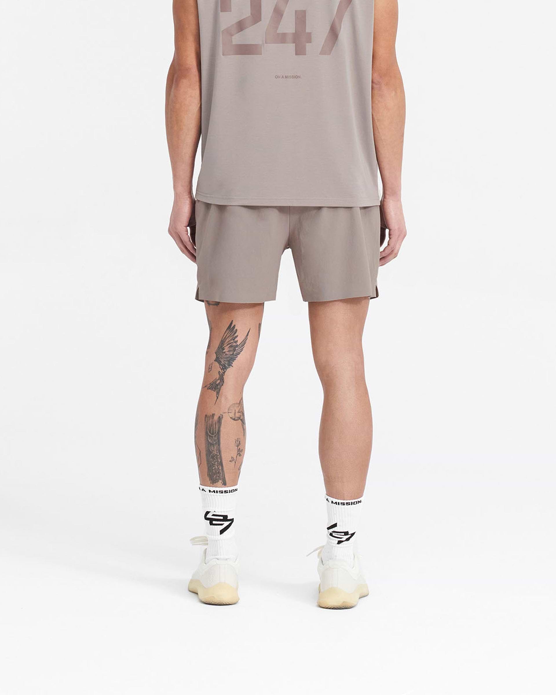 Man wearing grey gym shorts on a plain white background | 247 Fused Shorts in Cinder | Gym shorts with 247 branded waistband and quick-dry fabric | 247 Shorts | Represent Clo